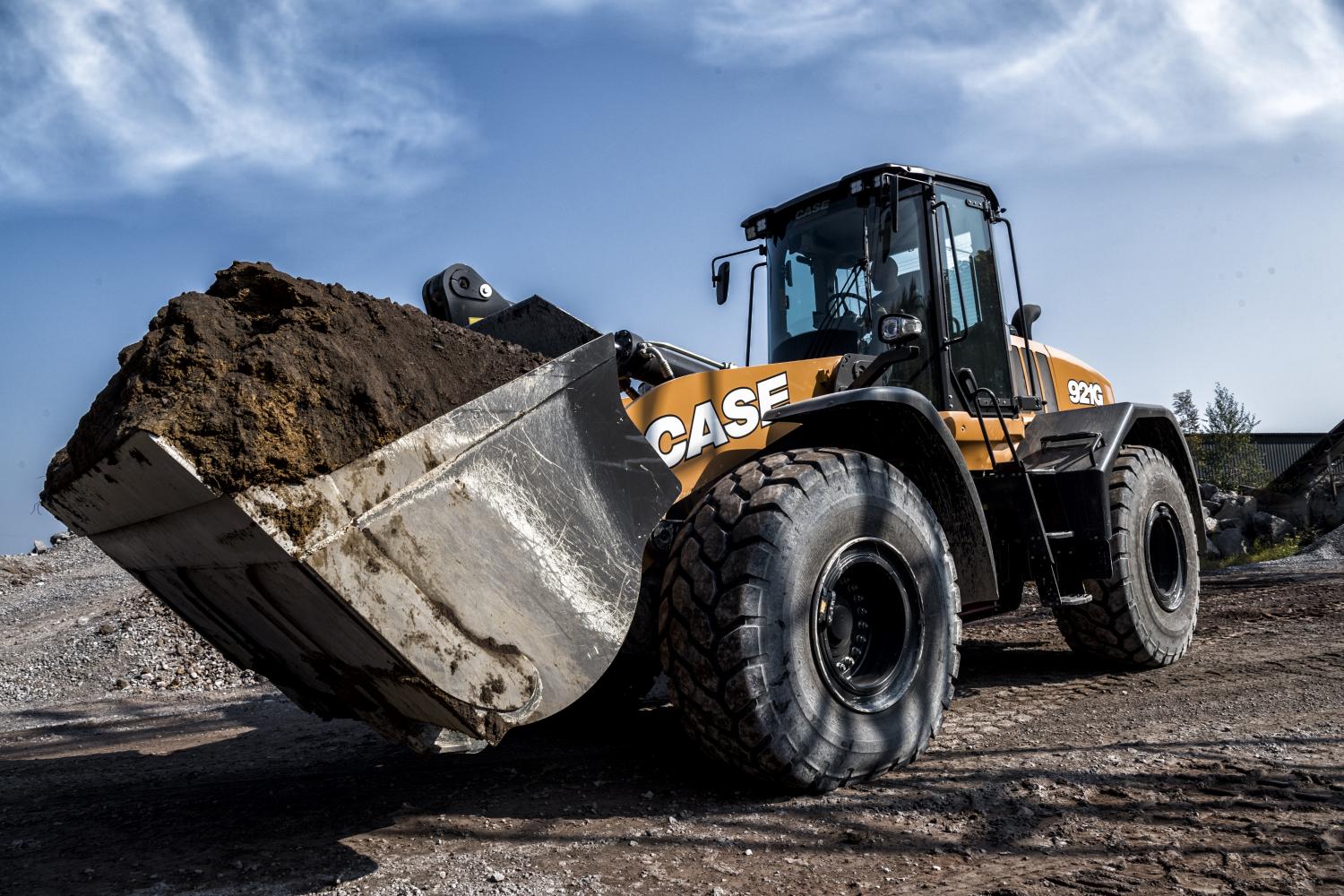 Case 921G wheel loader with full dirt bucket on a construction site.