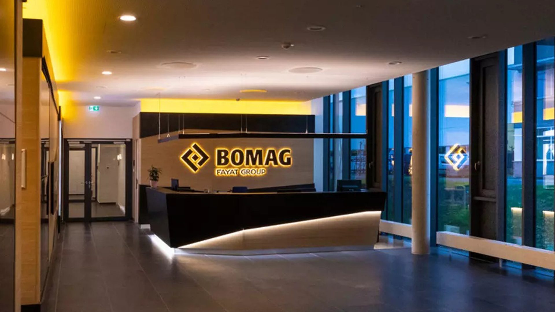 Modern reception with illuminated BOMAG FAYAT GROUP logo and sleek black desk.