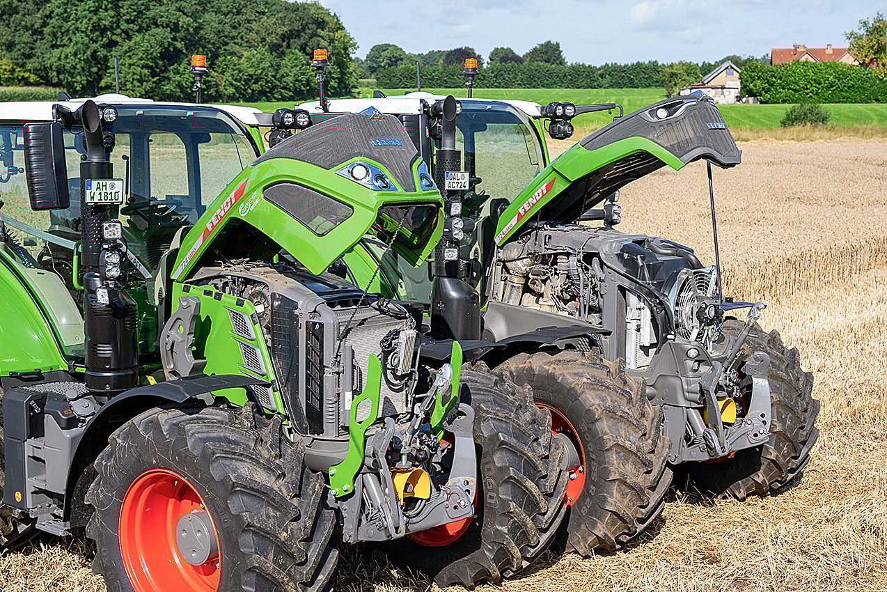 Two green Fendt tractors with open hoods showing their engines, parked in a field.