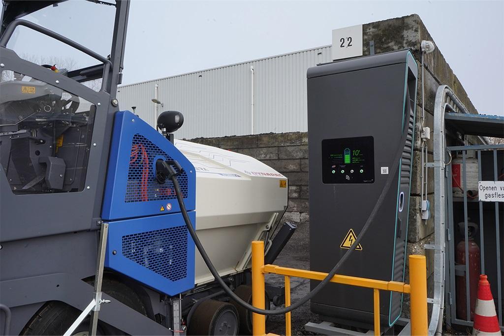 Electric construction vehicle charging at a large outdoor station.