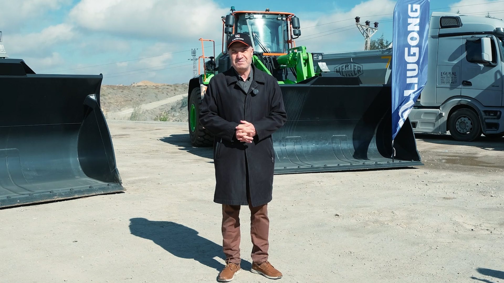 Man with construction loader, buckets, and a LIUGONG flag.
