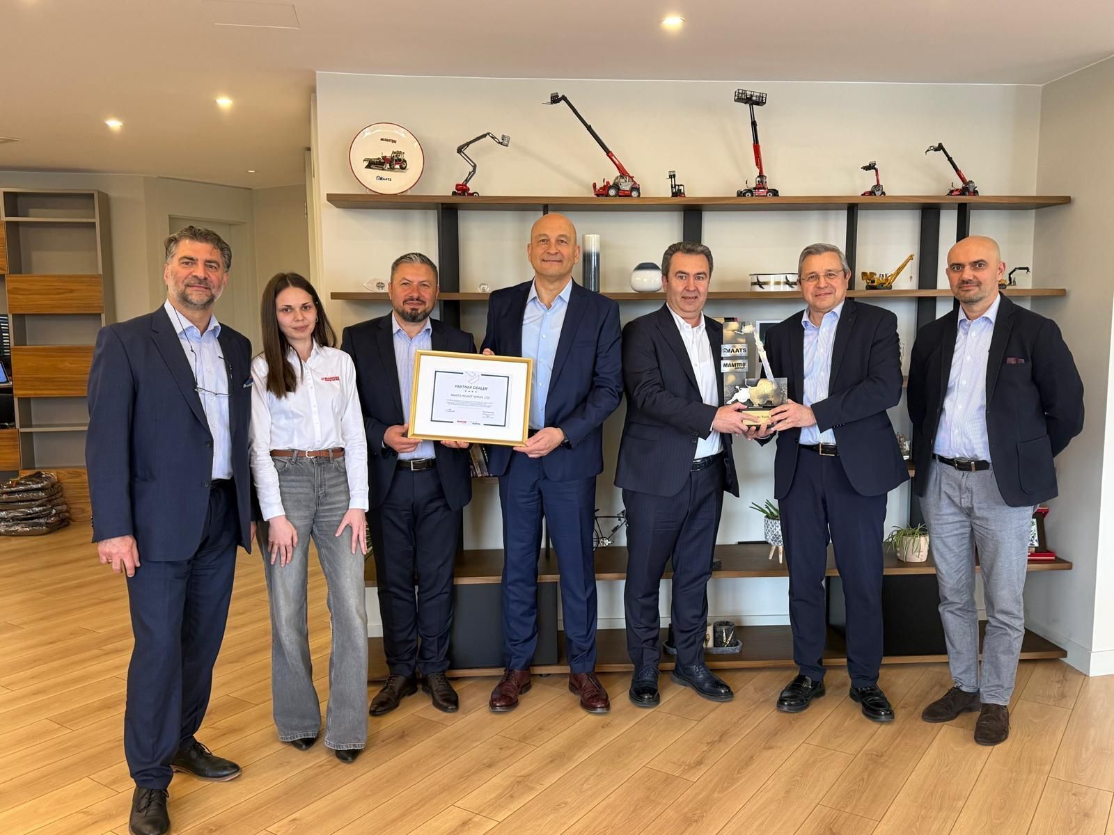 Group of seven people receiving awards and certificates in an office.