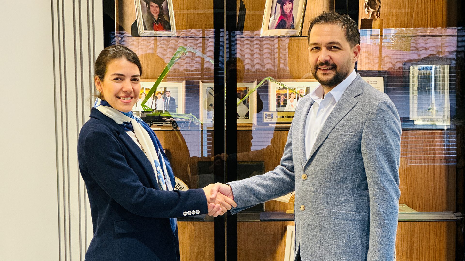 Smiling woman and man shaking hands in an office.