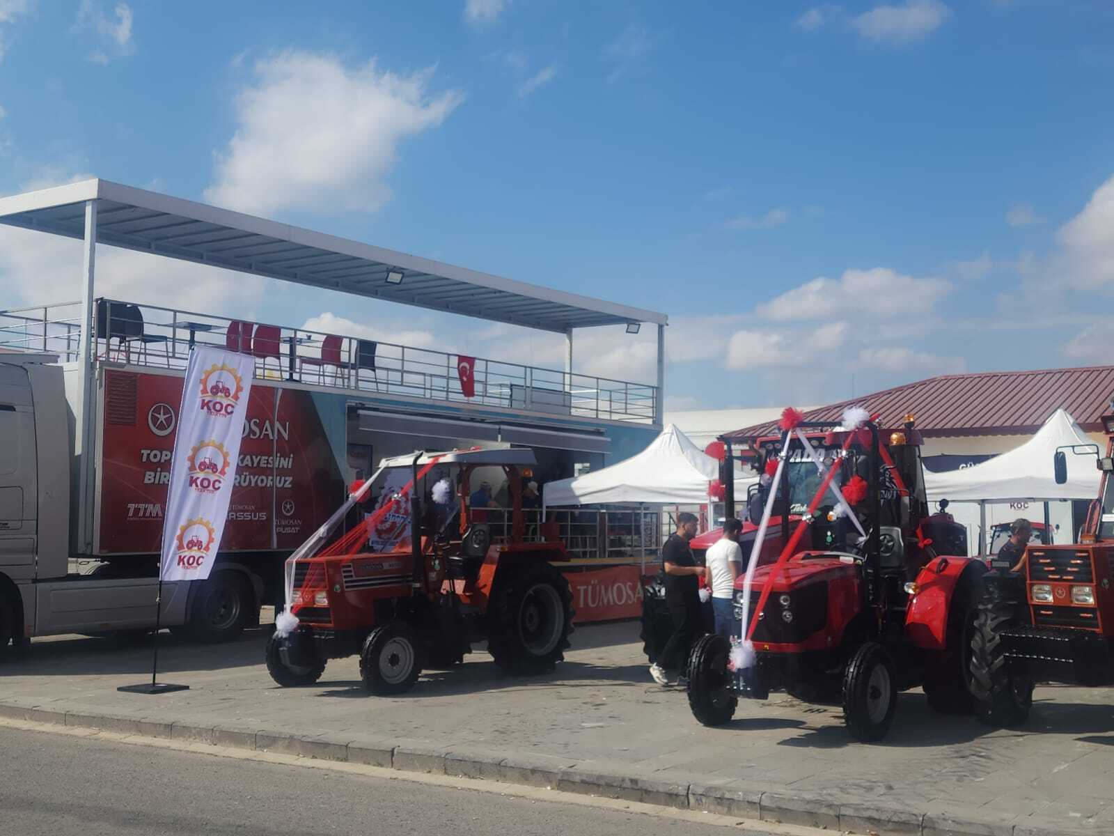 Decorated red tractors and a promotional truck at an outdoor event.