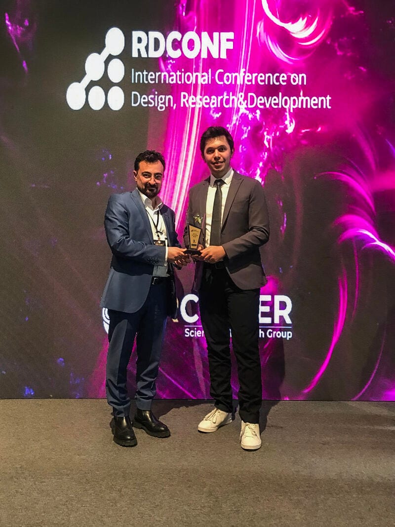 Two men on stage at RDCONF, one presenting a trophy to the other.