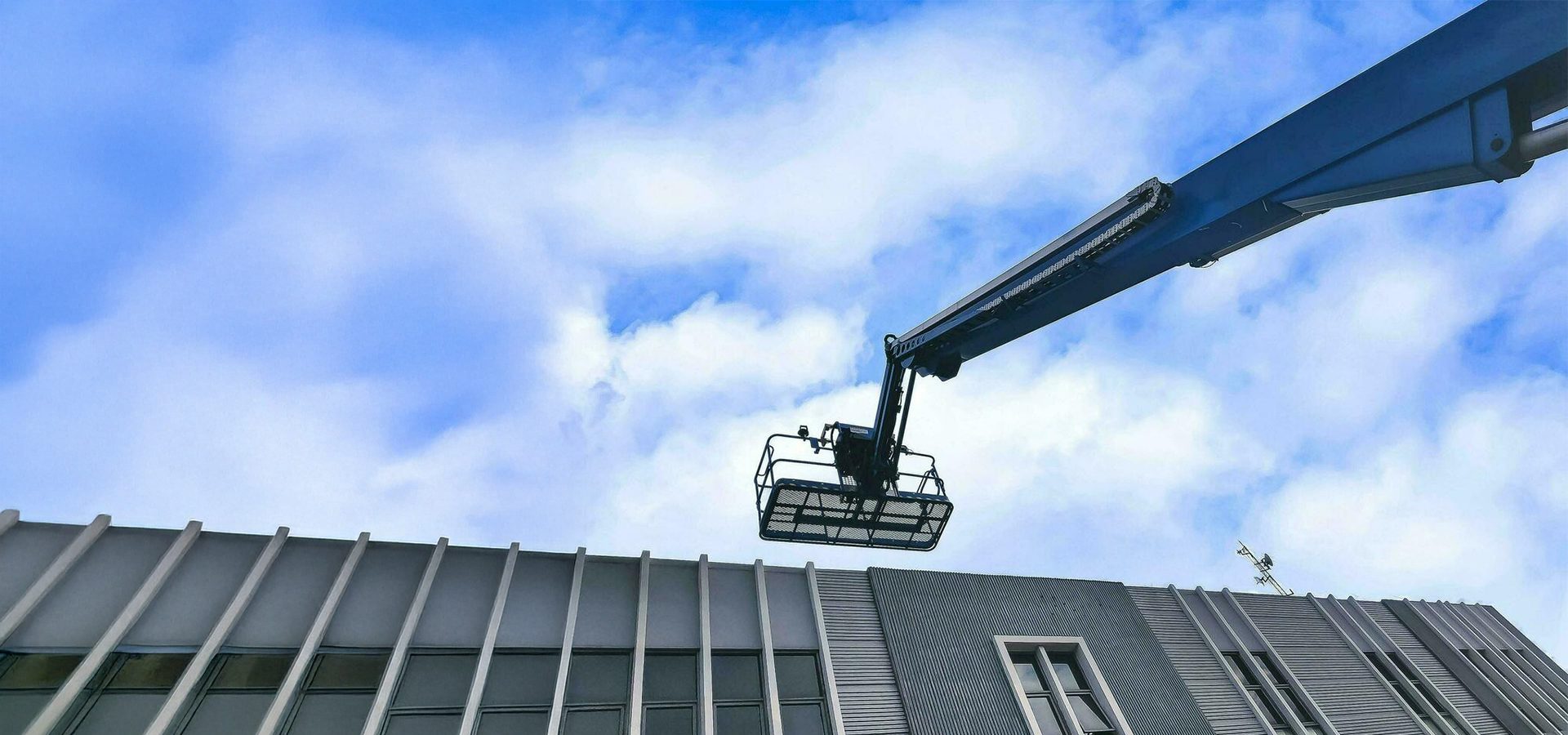 Cherry picker platform over modern building facade.