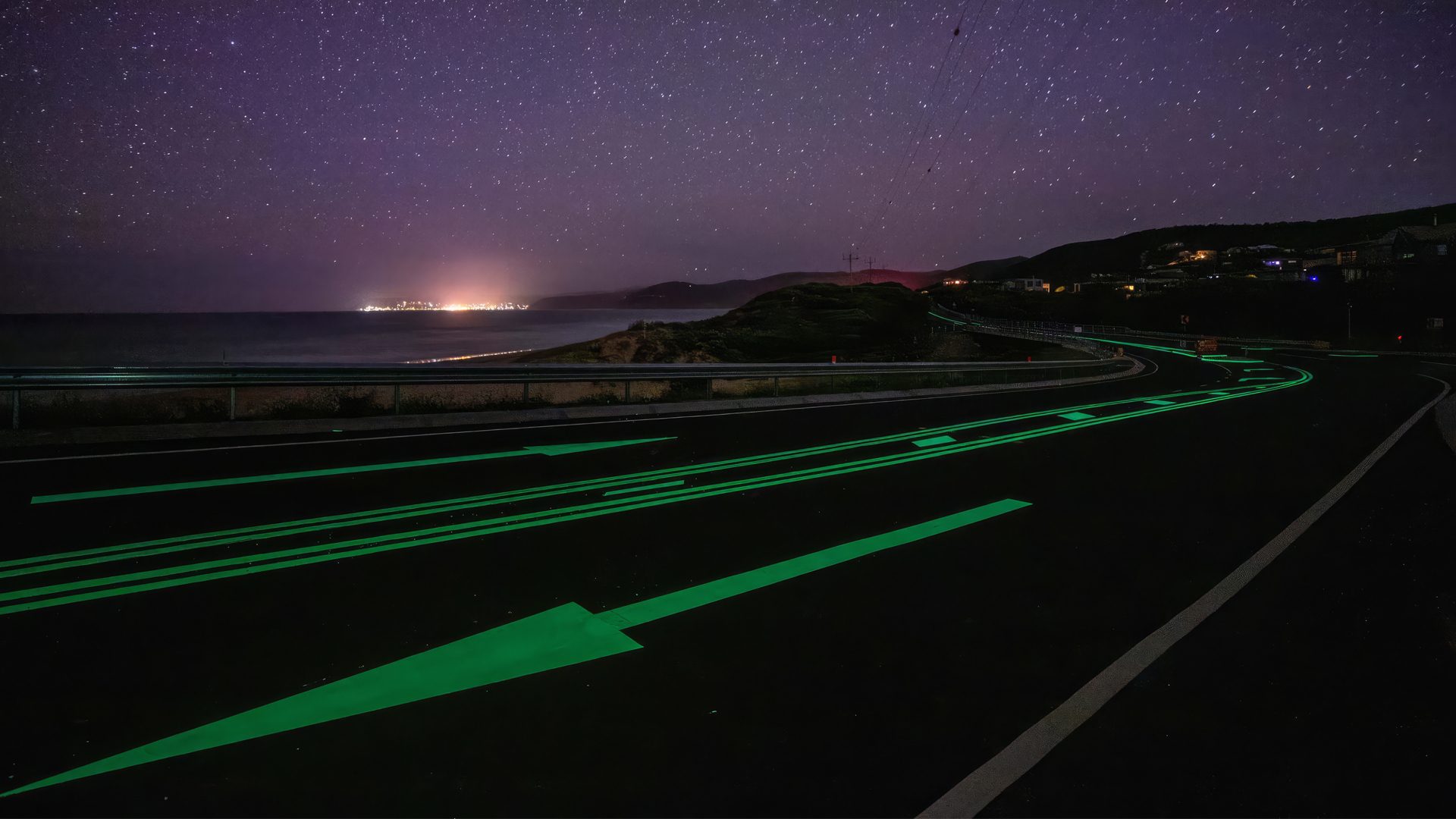 Starry night over a coastal road with bright green glowing lines and arrows. Distant city lights.