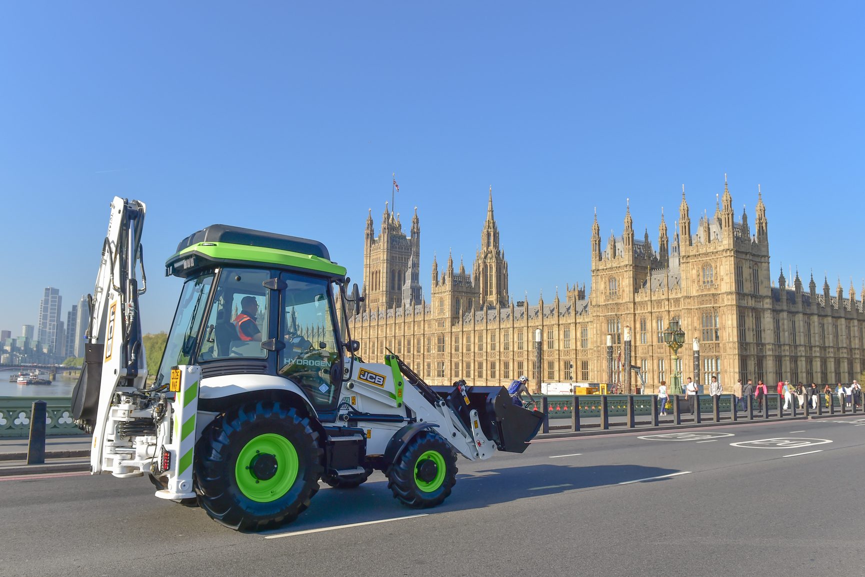JCB hydrogen backhoe on Westminster Bridge, with Houses of Parliament in London.