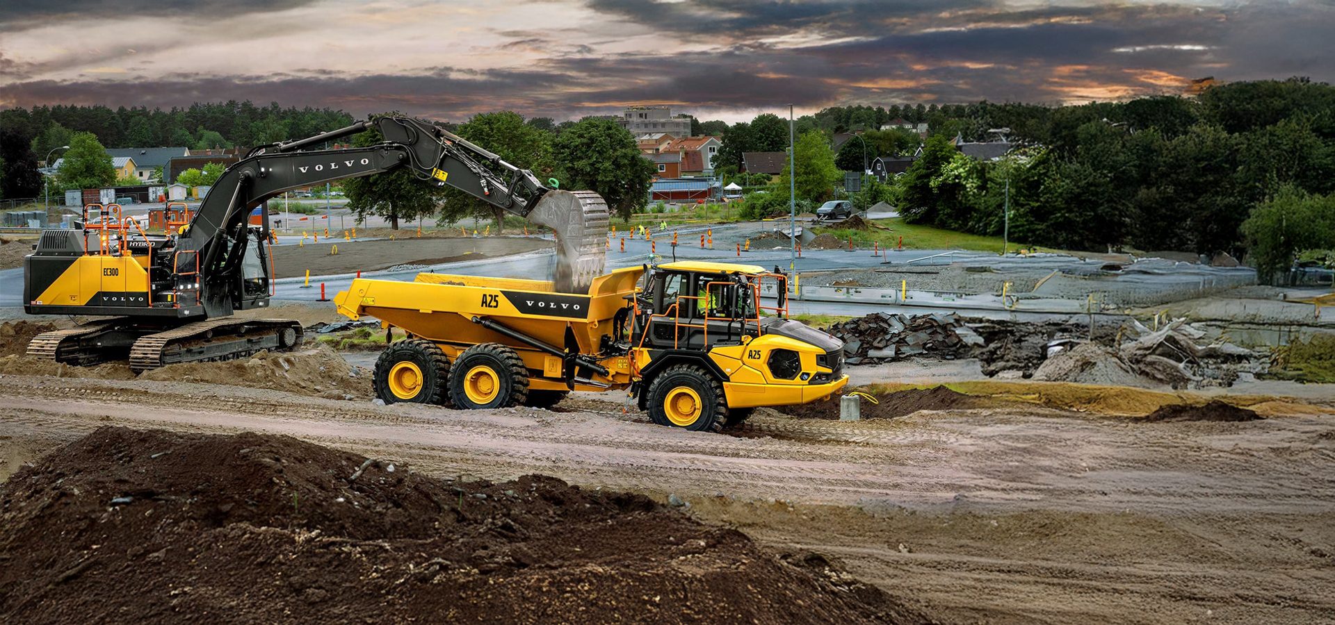 Excavator loading dirt into a Volvo articulated hauler on a construction site.