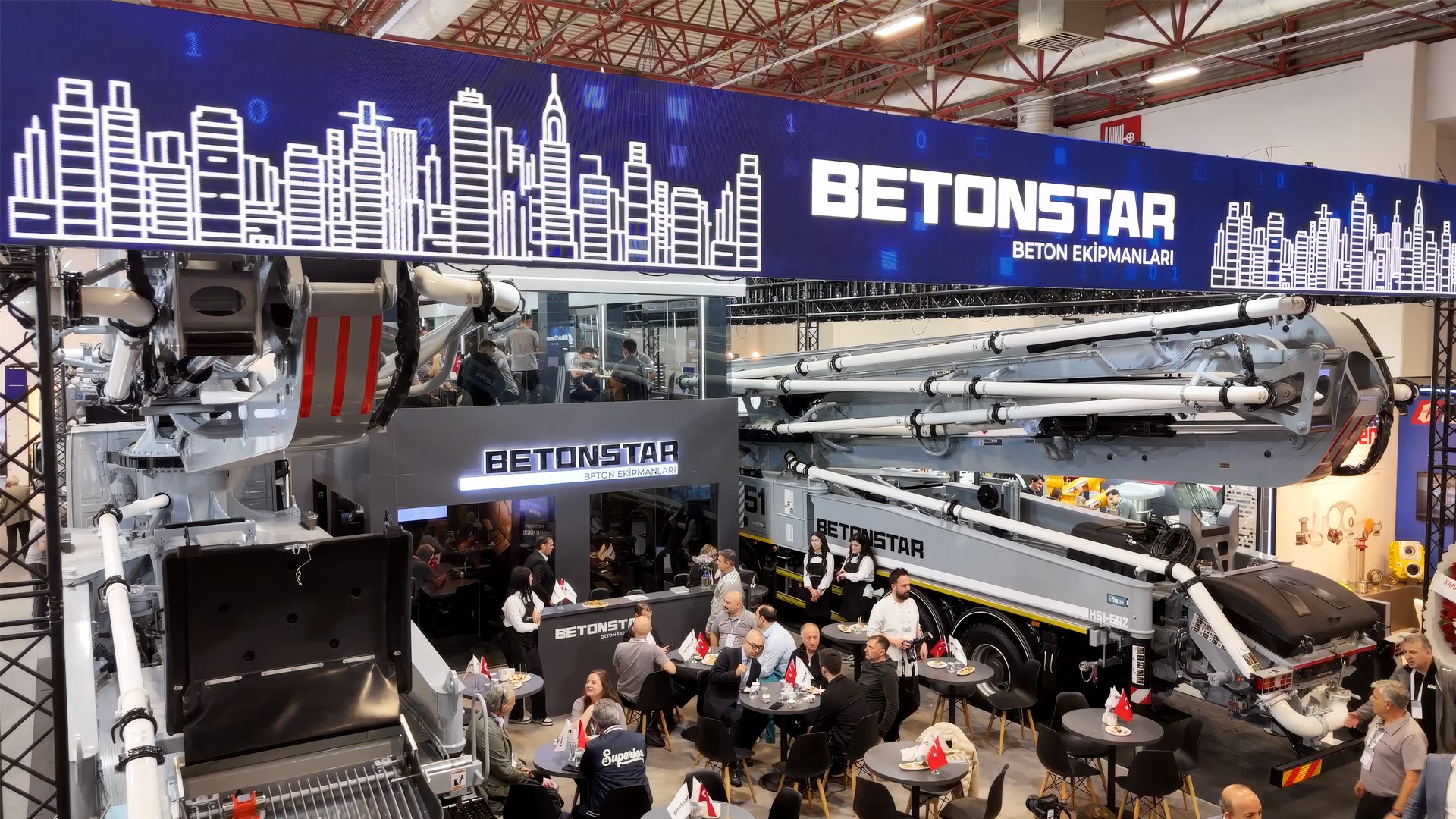 BETONSTAR exhibition booth with a large concrete pump truck, a banner, and people networking.