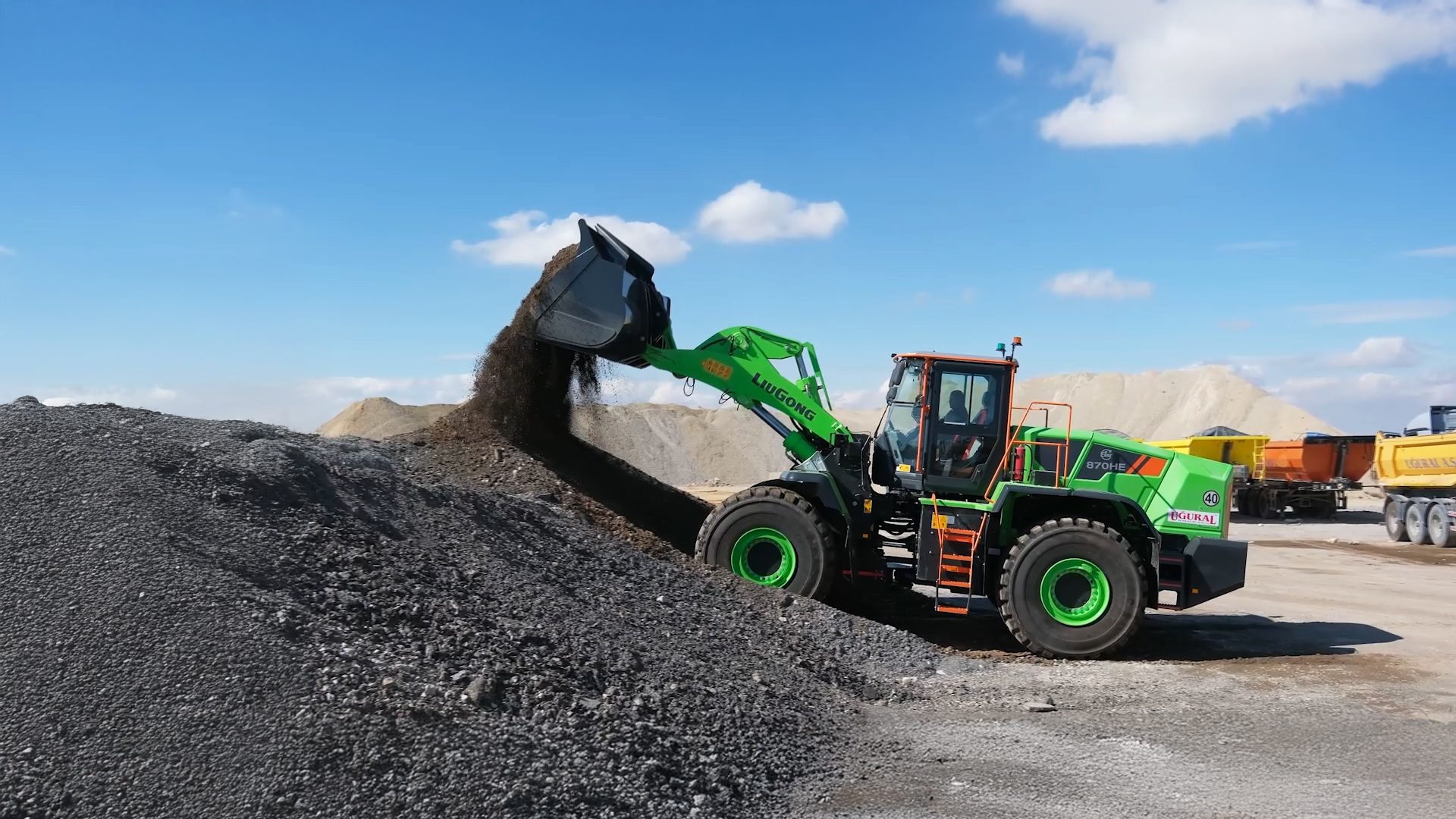 Green LiuGong wheel loader dumping dark gravel onto a large pile at an industrial site.