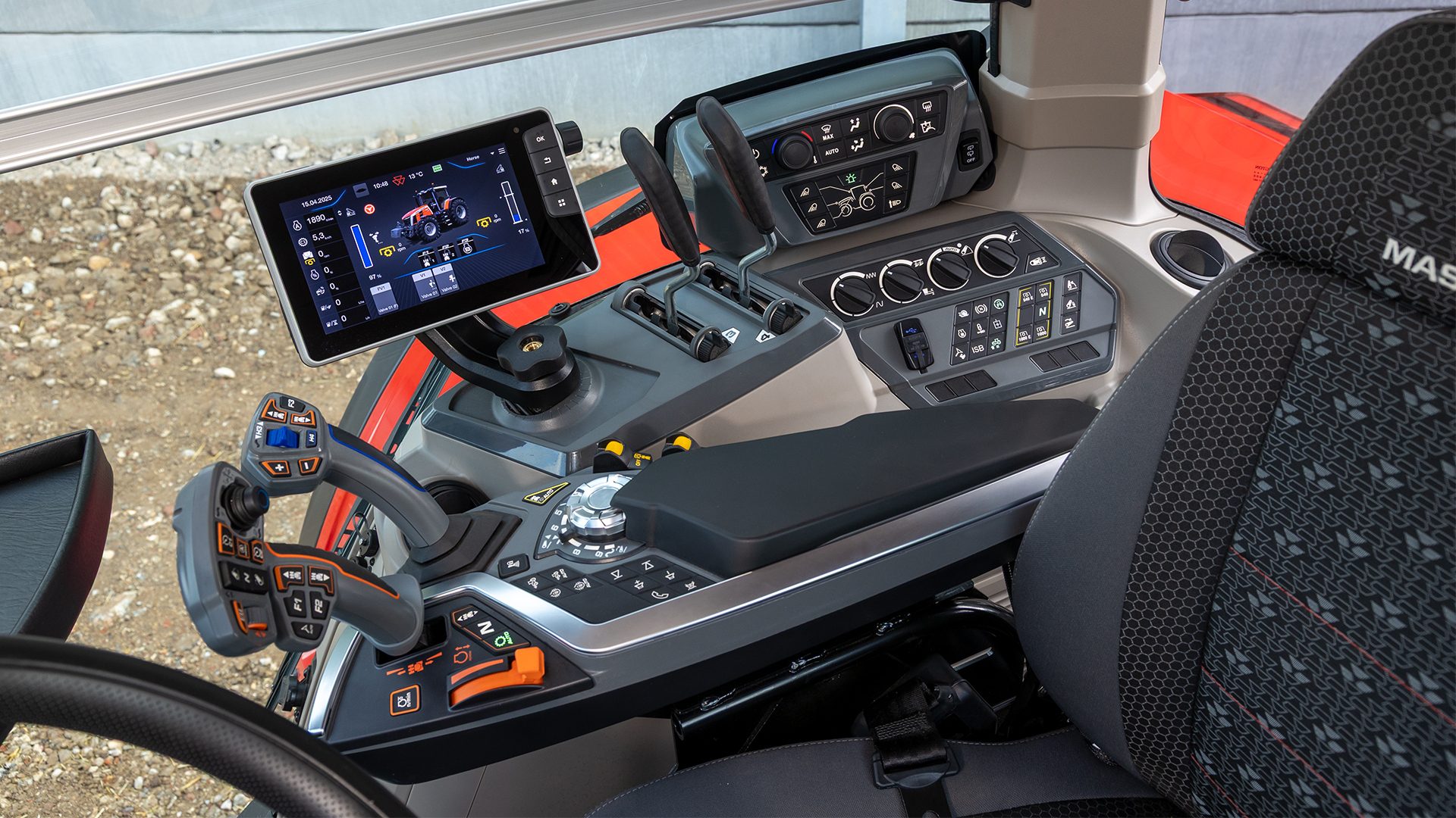 Modern tractor cabin interior with a digital display, control panel, and joysticks.