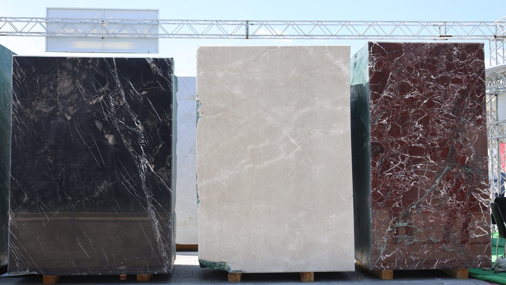 Three large marble slabs in black, beige, and reddish-brown colors with distinct veining patterns.