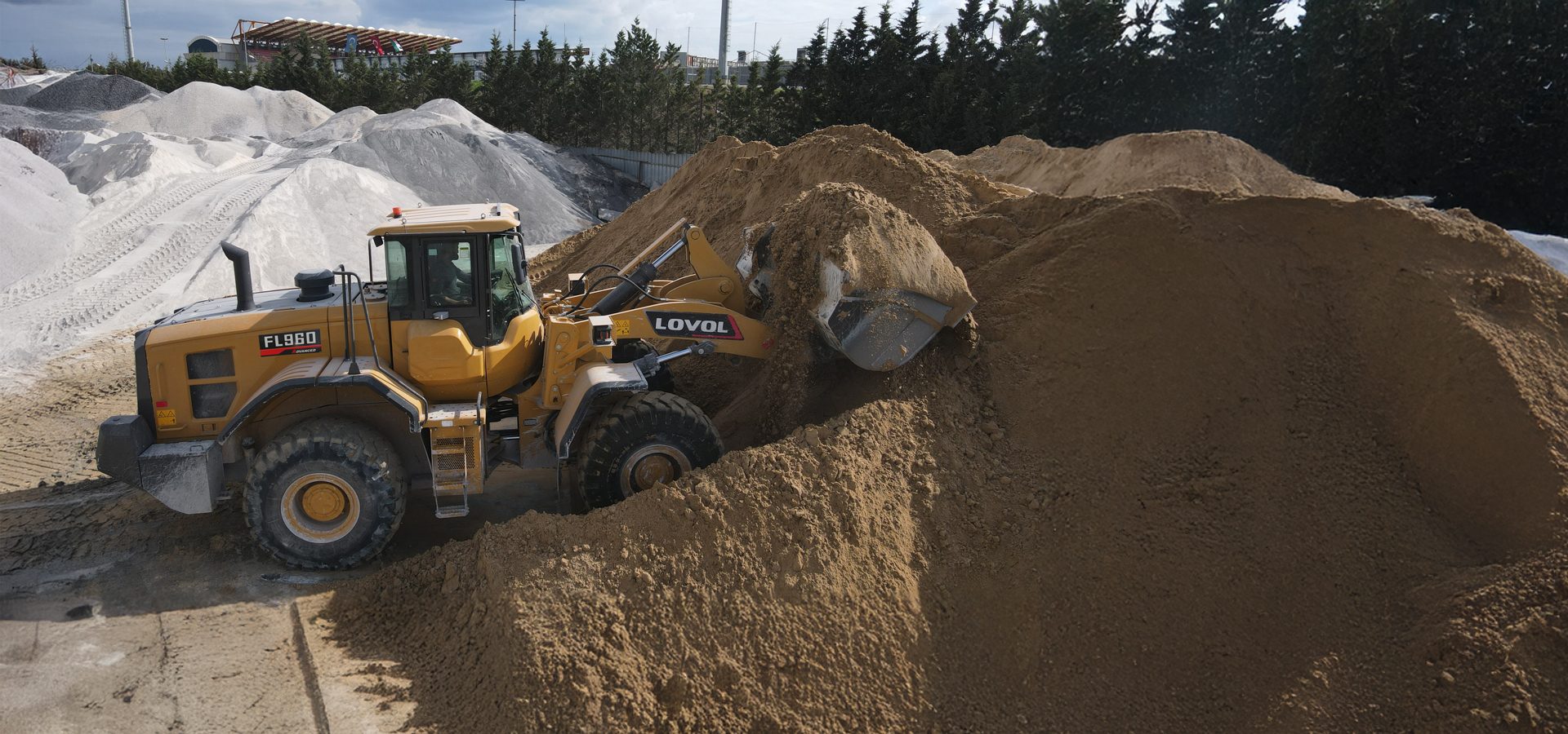 Yellow LOVOL FL960 loader scooping sand from a large pile.