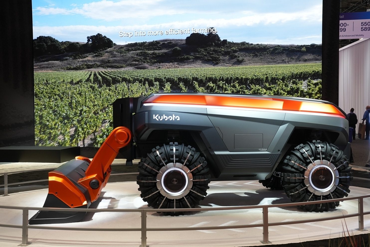 Futuristic orange and gray Kubota autonomous farm robot with unique wheels, displayed with an "efficient farming" screen.