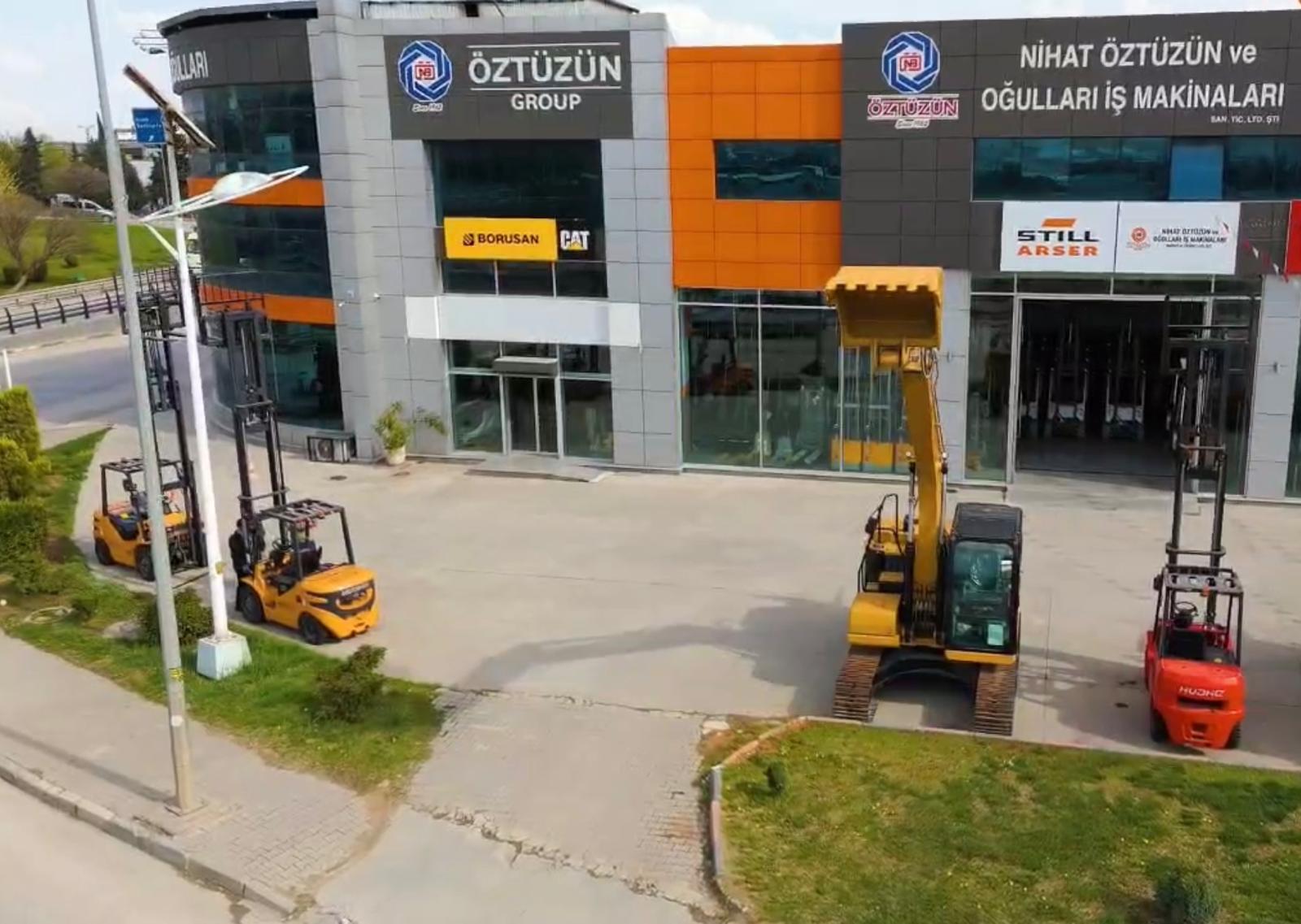 ÖZTÜZÜN Group machinery dealership with excavators and forklifts displayed outside.