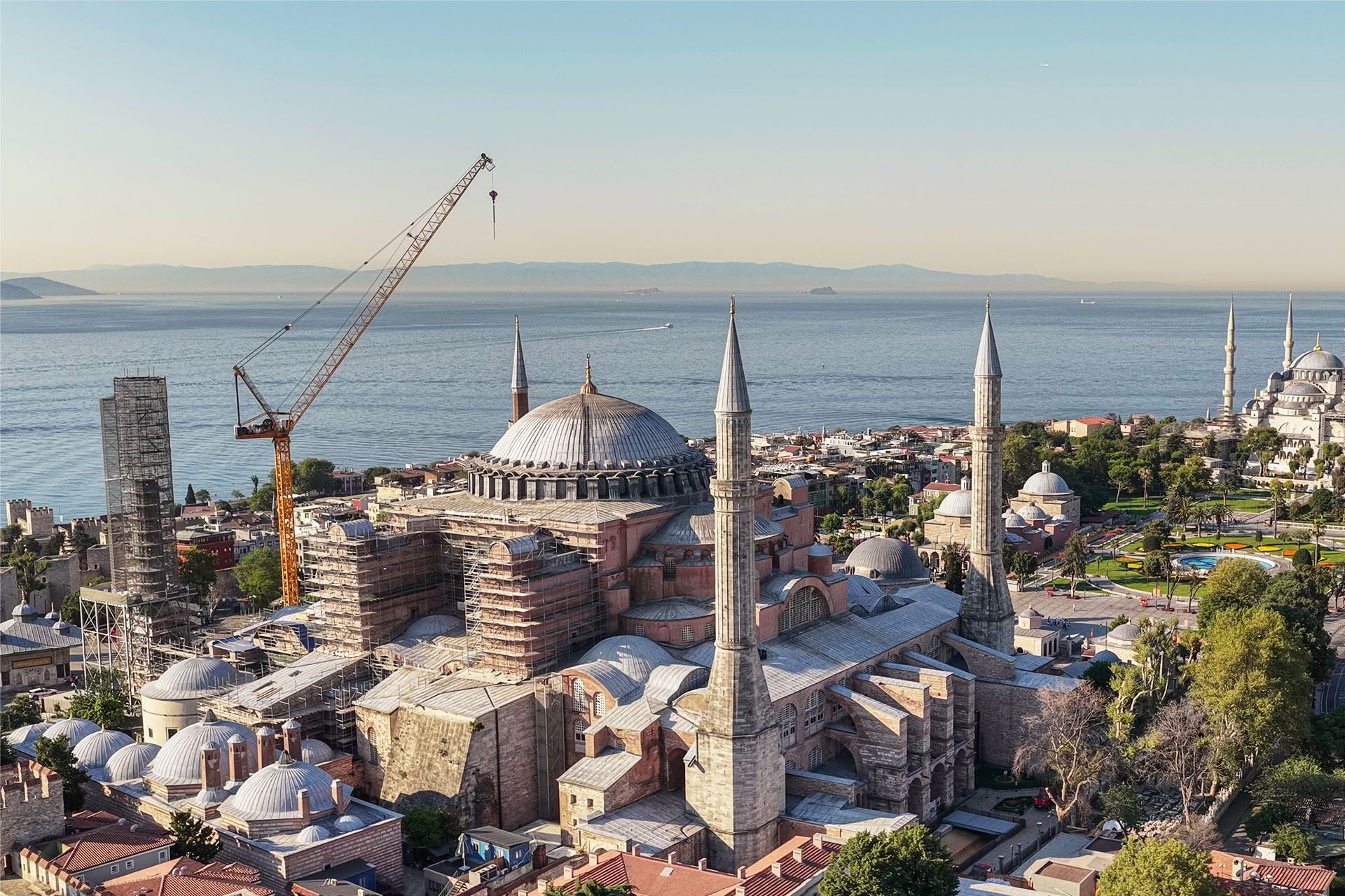 Aerial view of Hagia Sophia with scaffolding and a crane, the Bosphorus, and Blue Mosque in Istanbul.