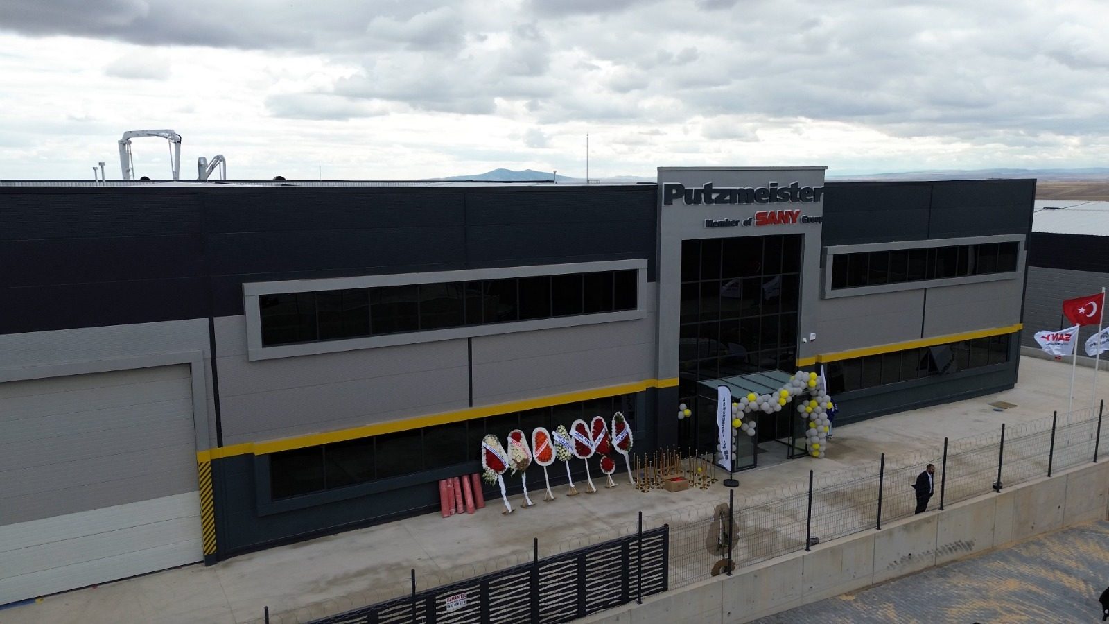 Modern Putzmeister & SANY industrial building with event decor, flags, and large mechanical arms visible above.