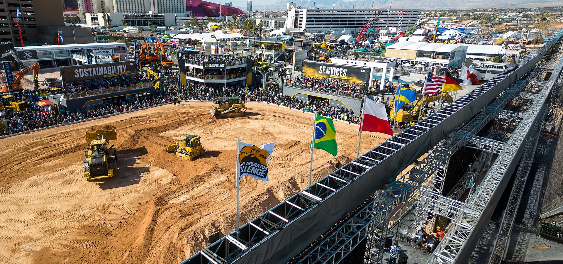 Construction equipment challenge with bulldozers, crowd, and international flags.