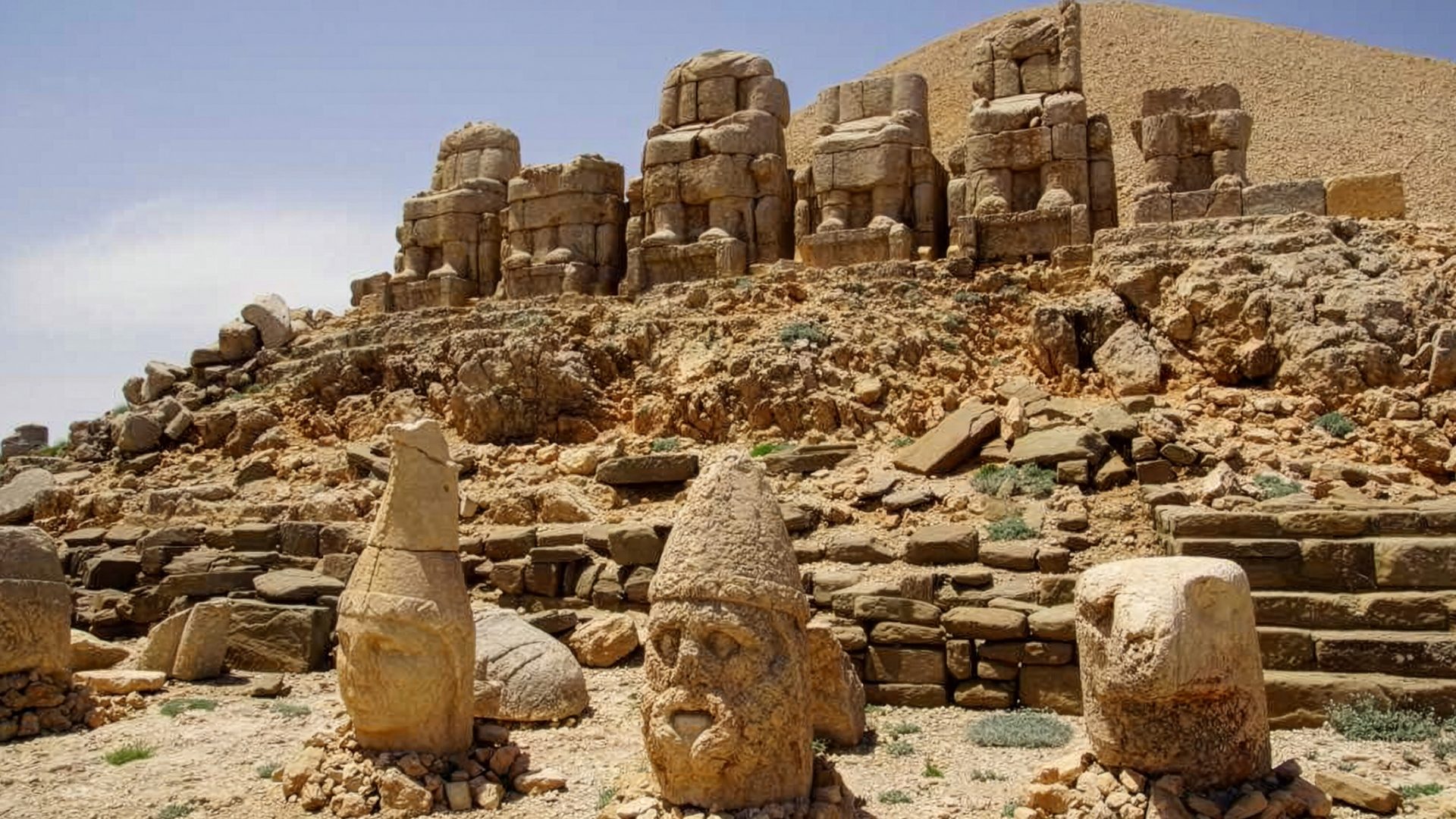 Colossal ancient stone heads and seated statues on Mount Nemrut's rocky slopes.