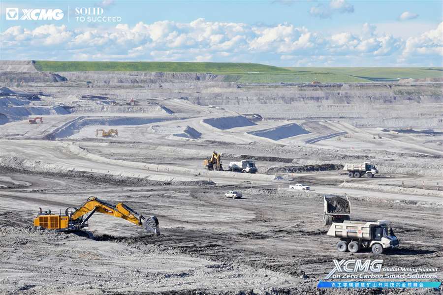 XCMG heavy machinery operating in a vast open-pit mine under a blue sky.