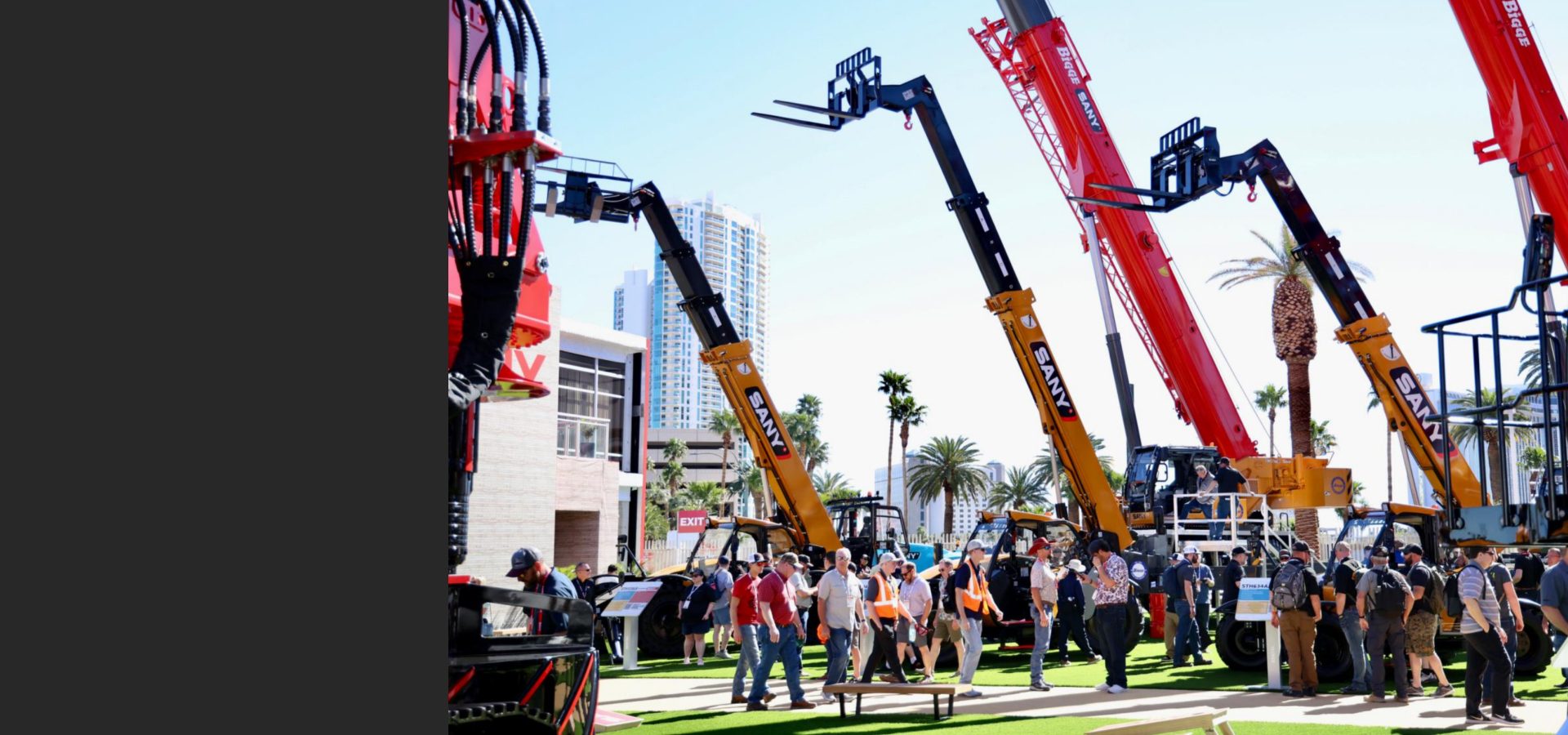 Outdoor exhibition with large SANY telehandlers and heavy construction machinery, attended by a crowd.