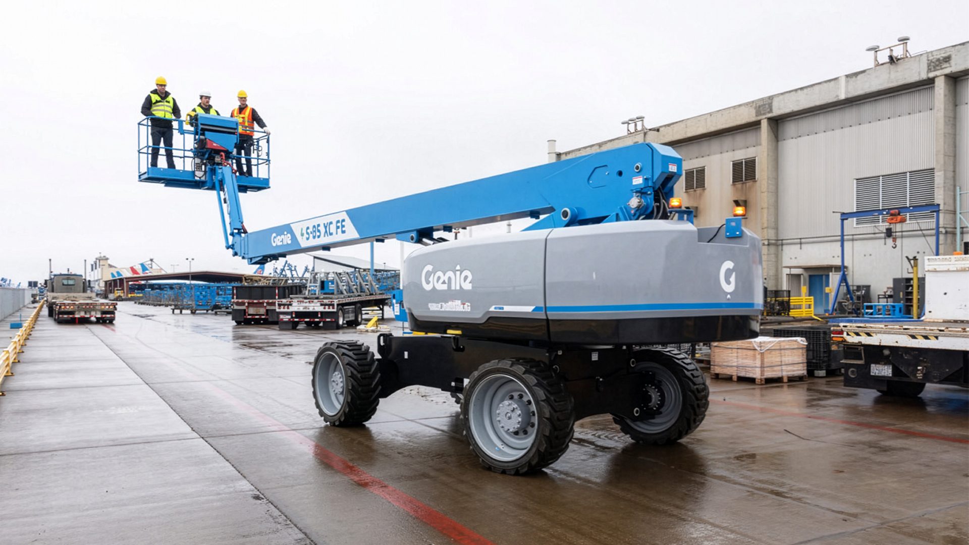 Three workers in a blue Genie boom lift with an extended arm at an industrial site.