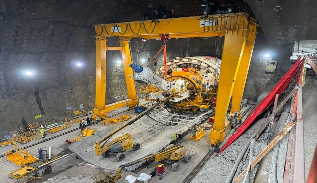Assembly of a large tunnel boring machine in an underground shaft with a gantry crane.