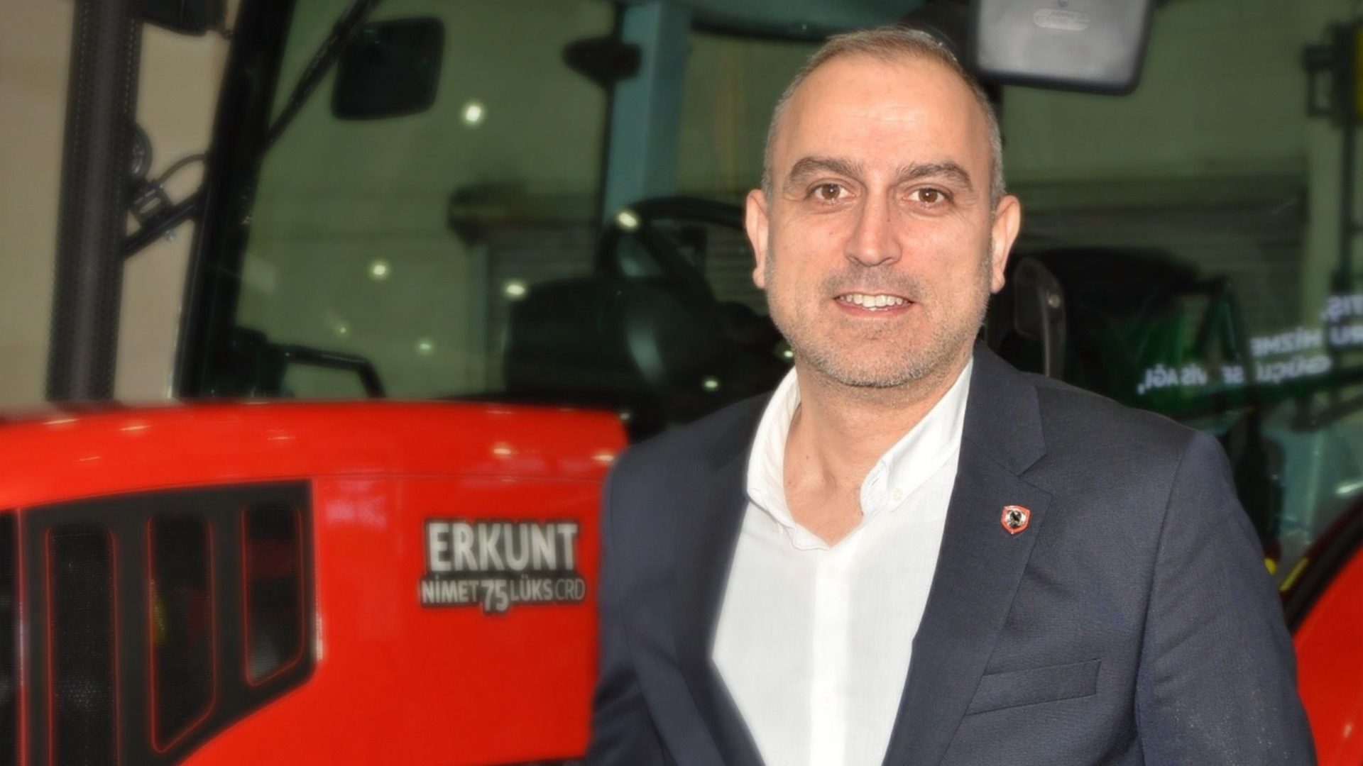 A man smiling next to a red Erkunt Nimet 75 Lüks CRD tractor.