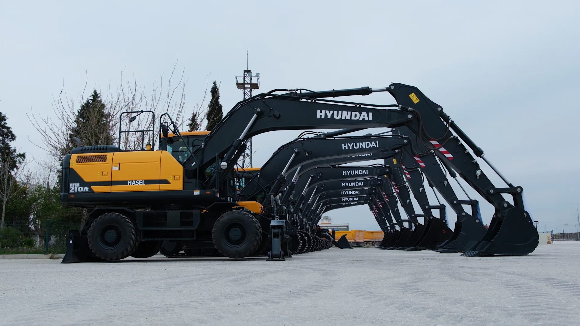 A line of new Hyundai wheel excavators, featuring yellow bodies and black arms, parked on an outdoor lot.