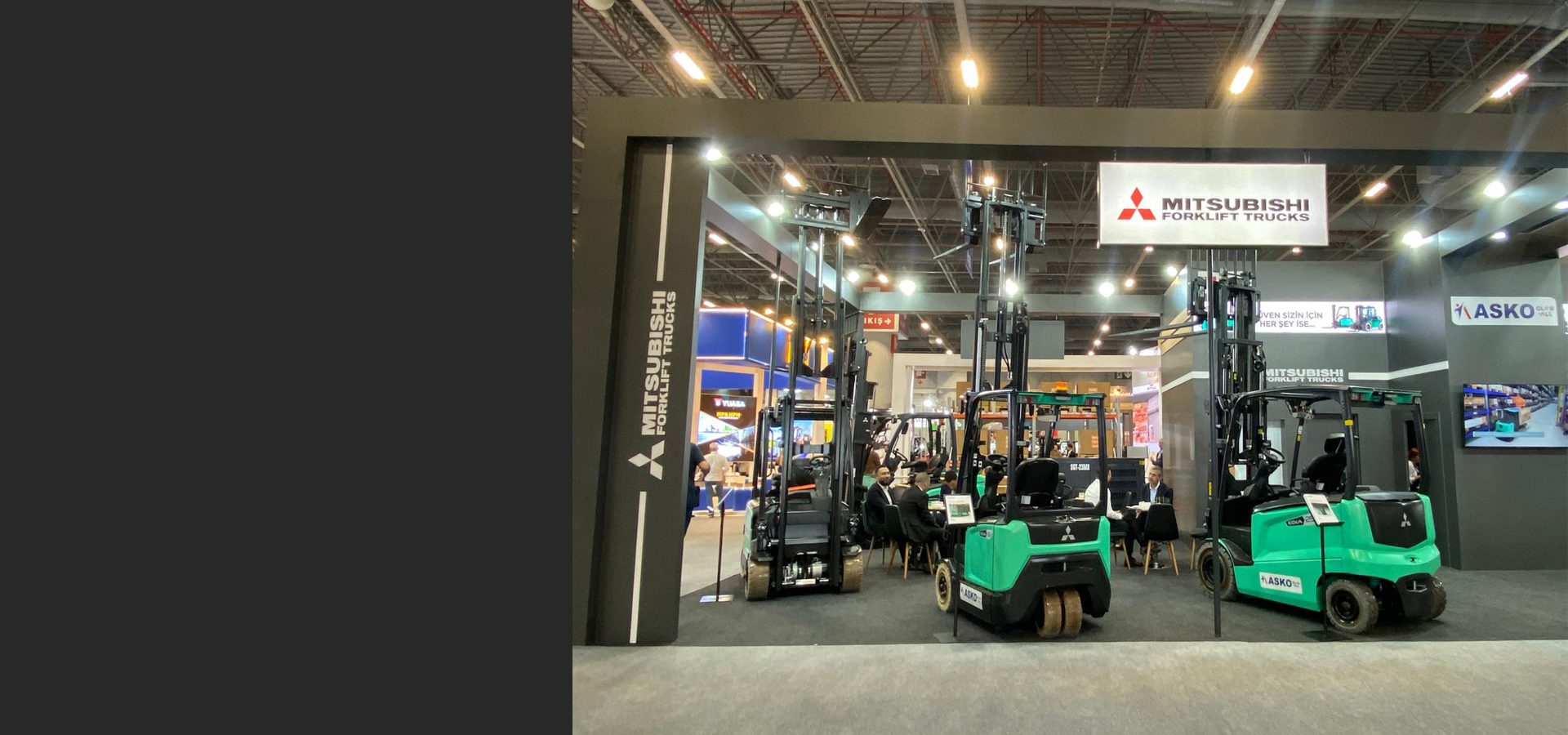 Mitsubishi Forklift Trucks exhibition booth showcasing green forklifts at a trade show.
