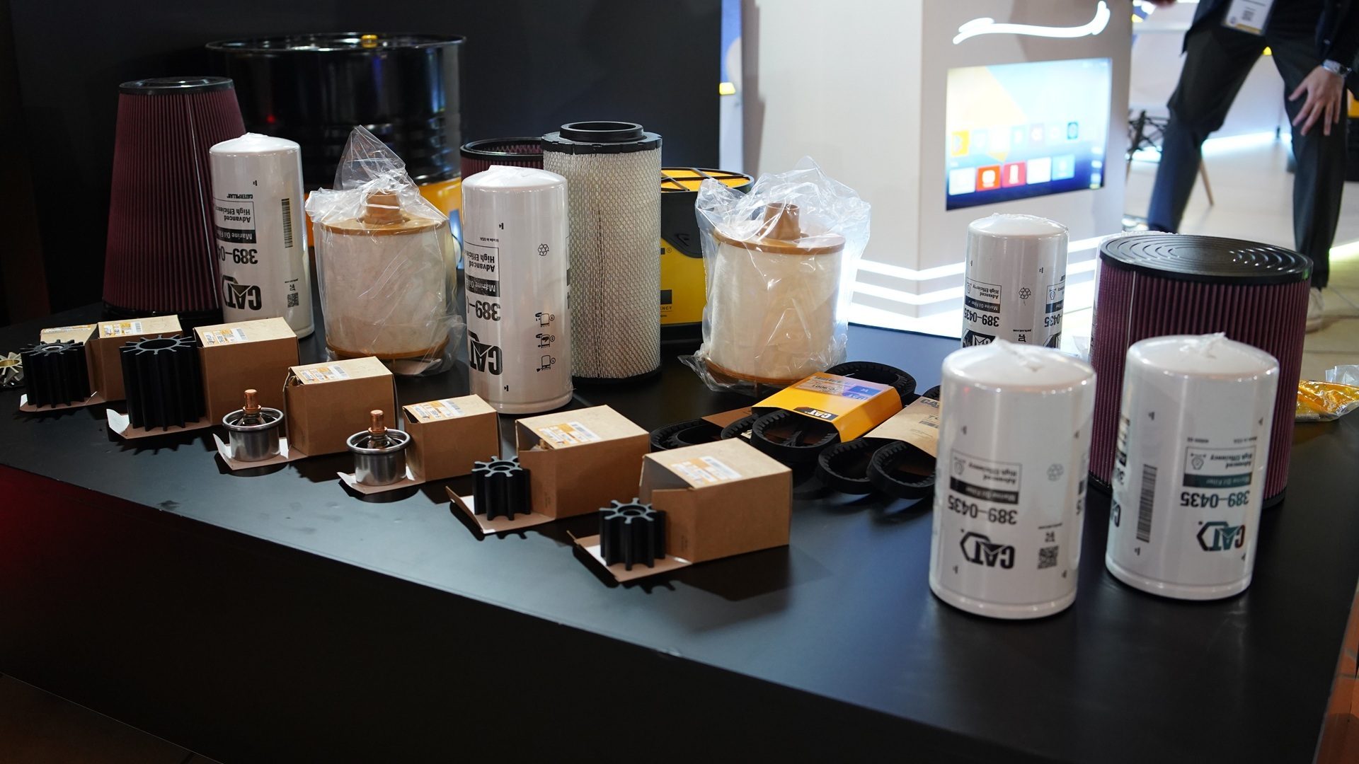Caterpillar (CAT) filters, belts, and various industrial parts displayed on a black table.