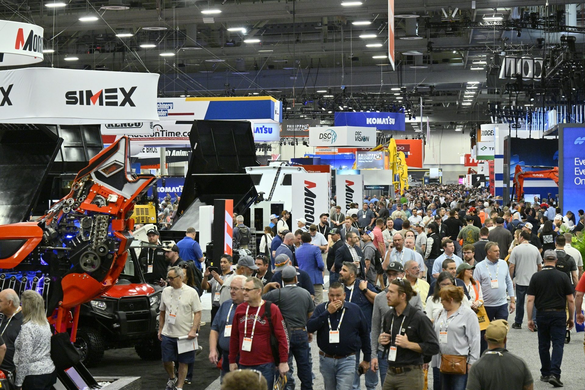A bustling industrial trade show floor with attendees viewing heavy machinery and equipment exhibits.