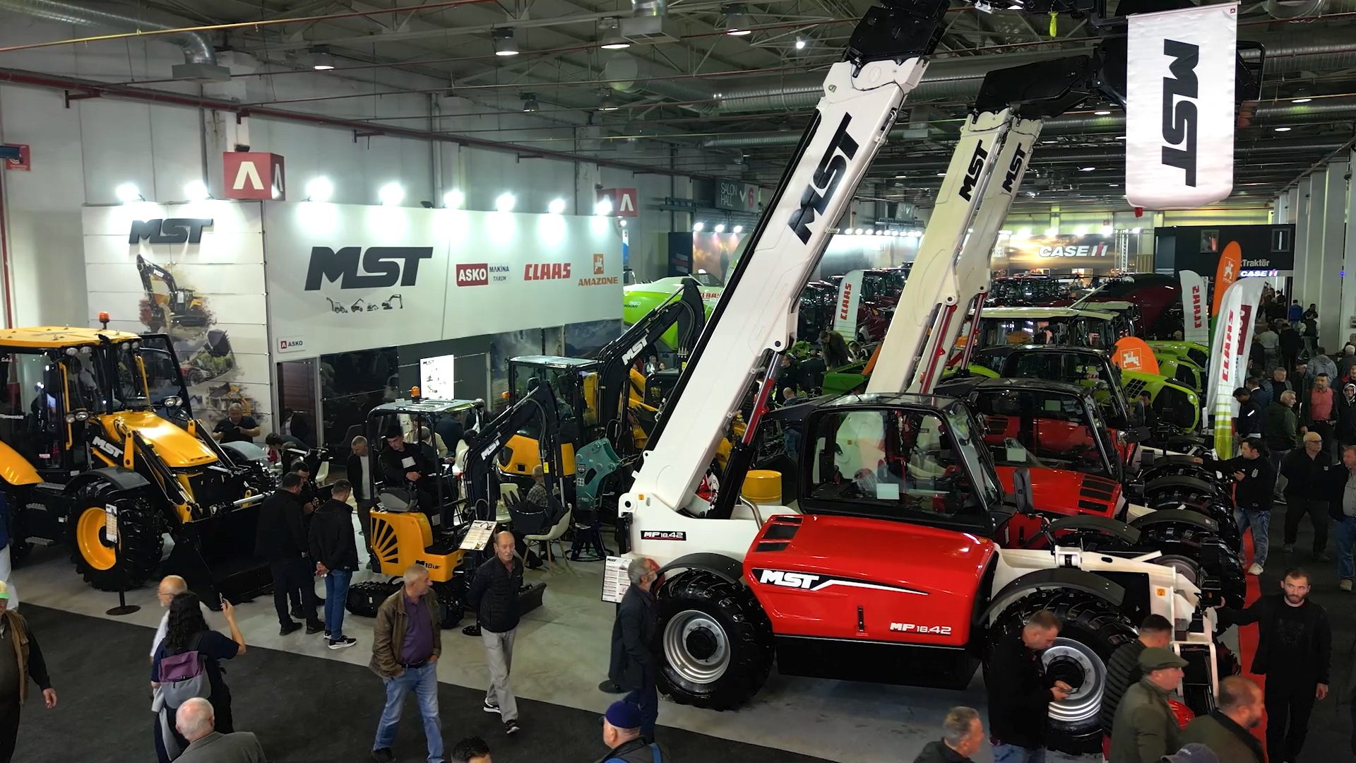 Heavy machinery trade show with MST brand equipment and attendees.