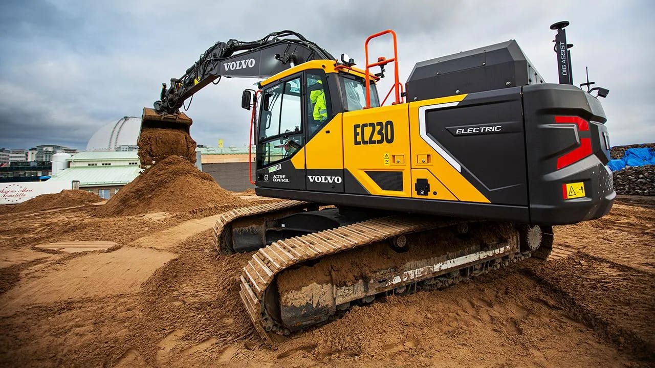 Volvo EC230 Electric excavator with a full bucket of dirt on a construction site.