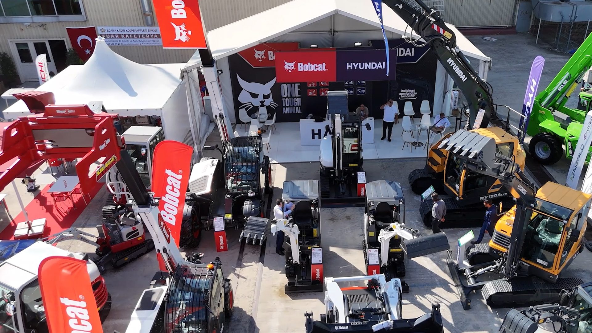 Outdoor exhibition of Bobcat and Hyundai heavy machinery, seen from above.