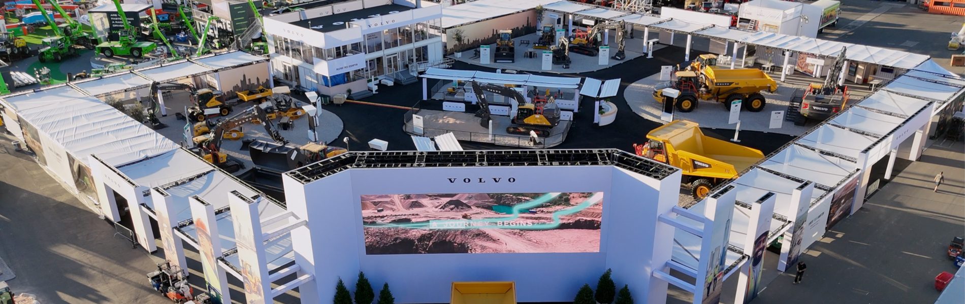 Overhead view of a large Volvo construction equipment exhibit with heavy machinery and a screen.