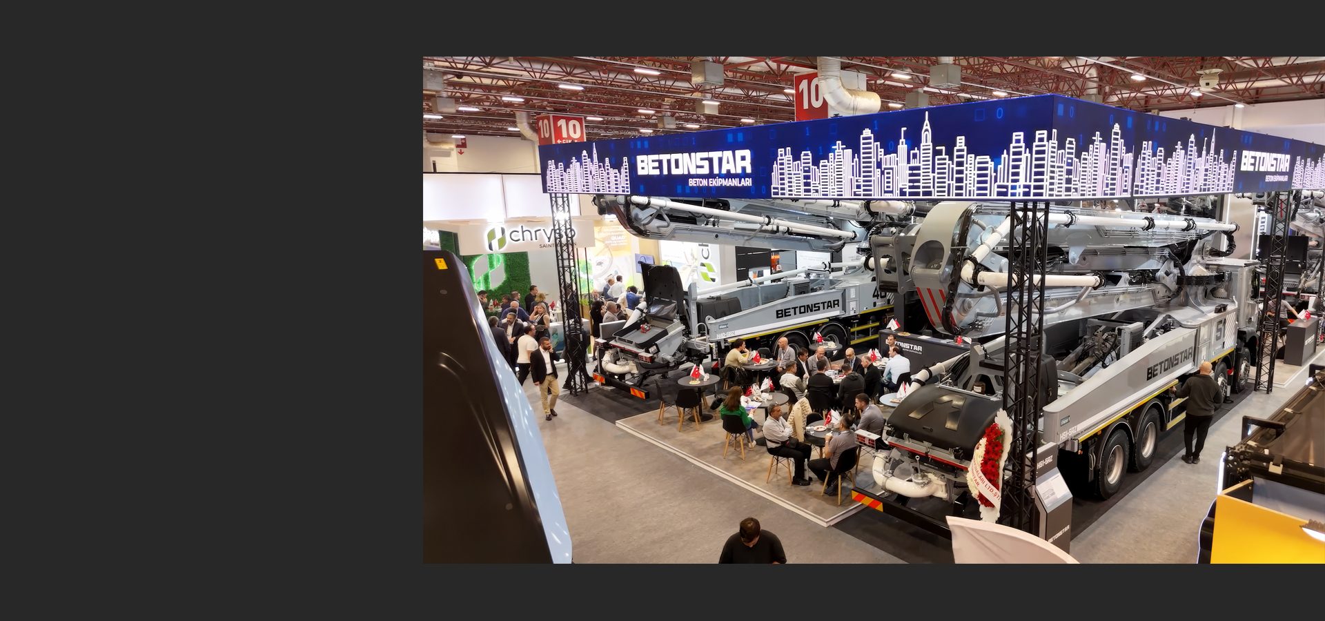 Overhead view of an exhibition hall featuring large BETONSTAR concrete pump trucks and attendees.