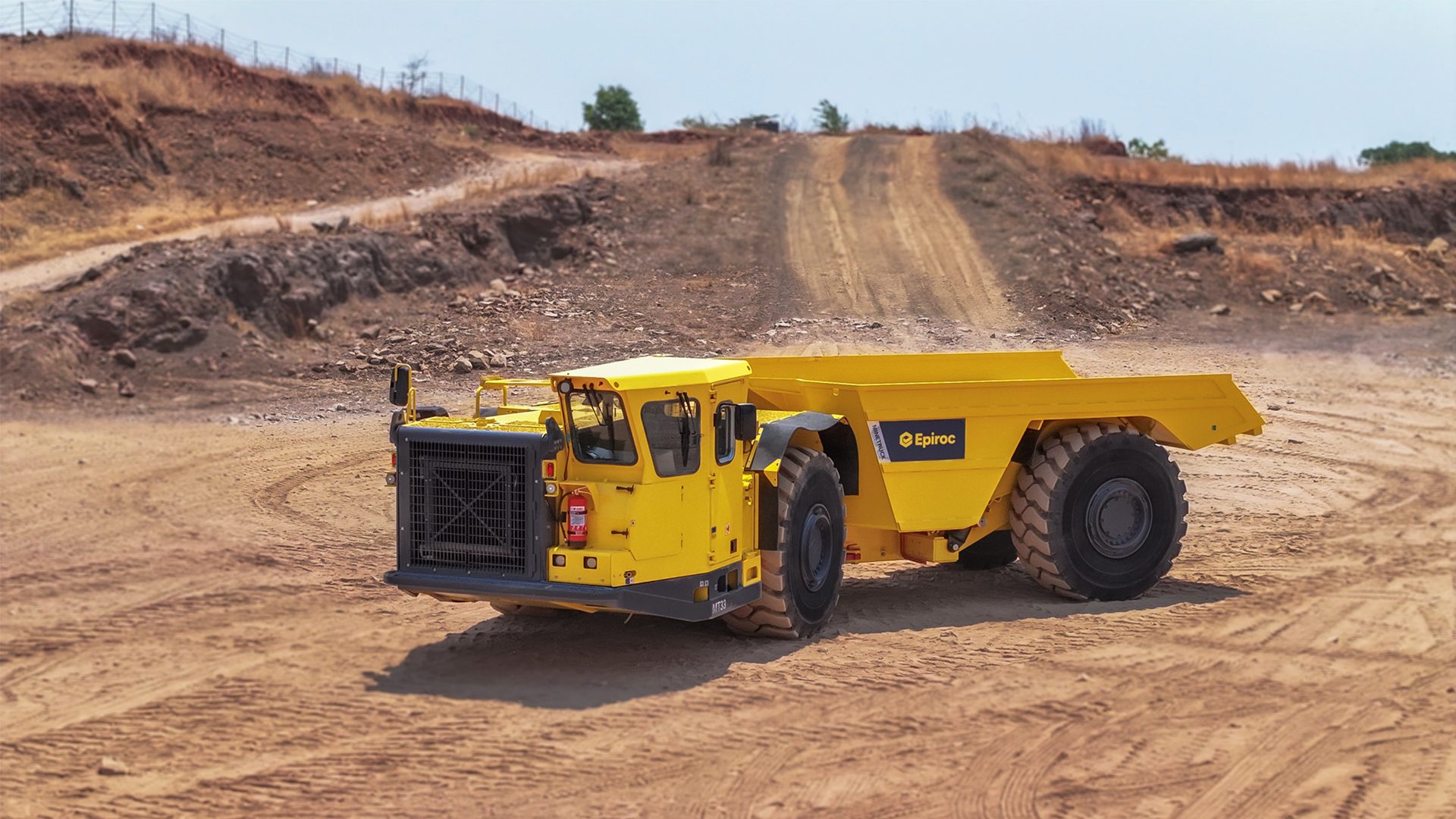 Yellow Epiroc mining dump truck in a dusty open-pit mine.