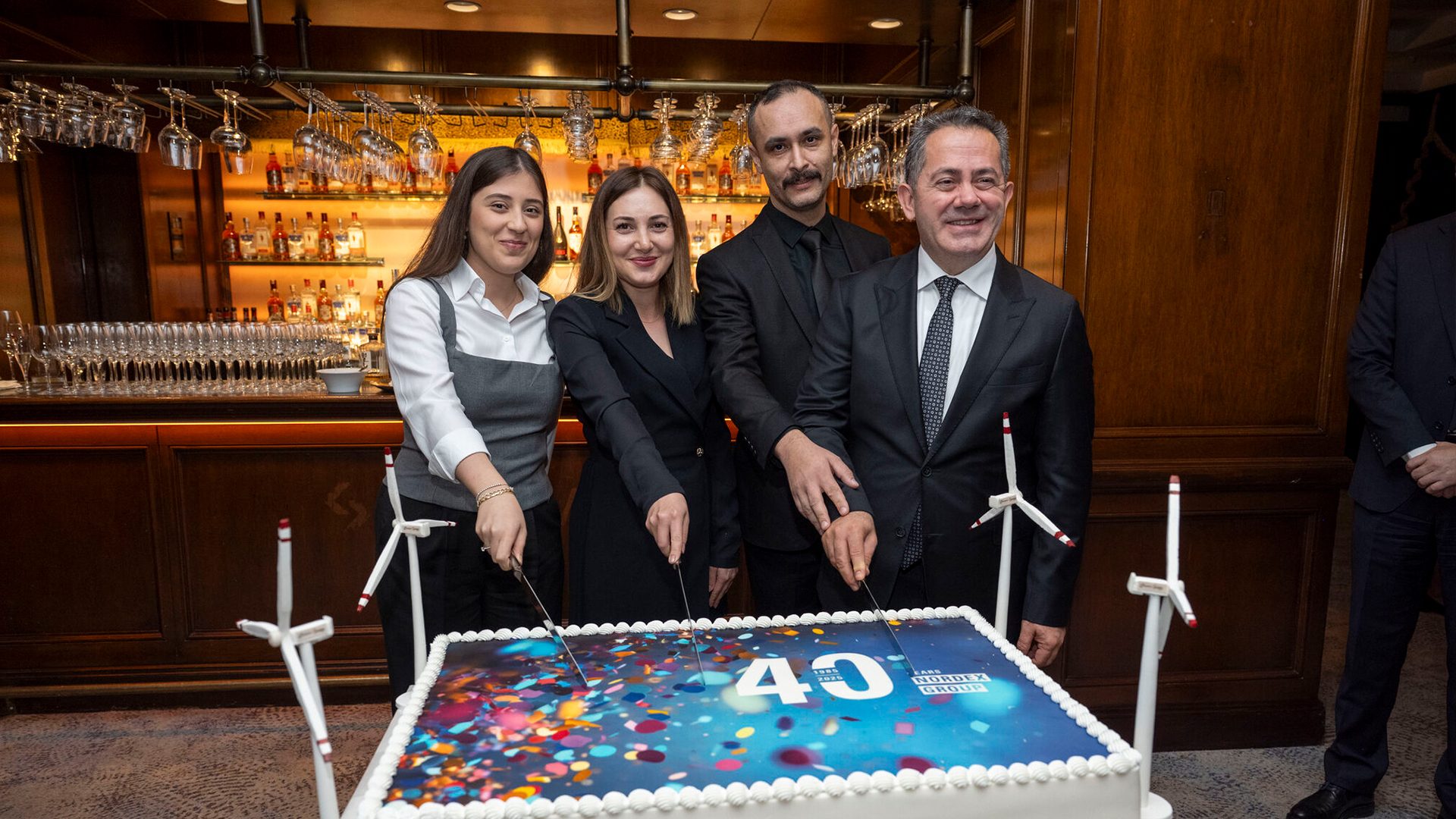 Four people cut a cake celebrating "40 Years Nordex Group", with wind turbine models.