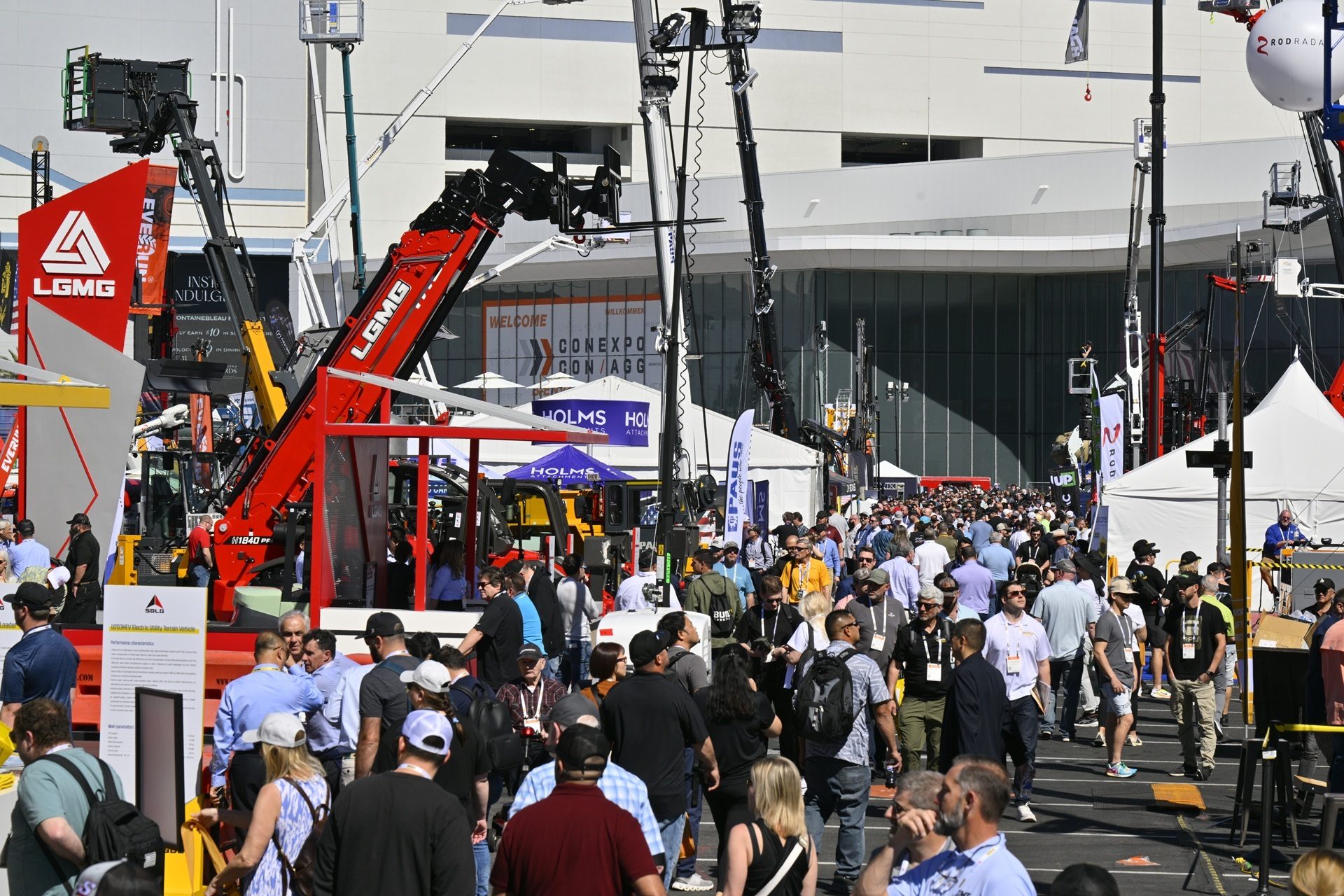 Crowds of people at the CONEXPO CON/AGG exhibition amidst large LGMG construction machinery and tents.