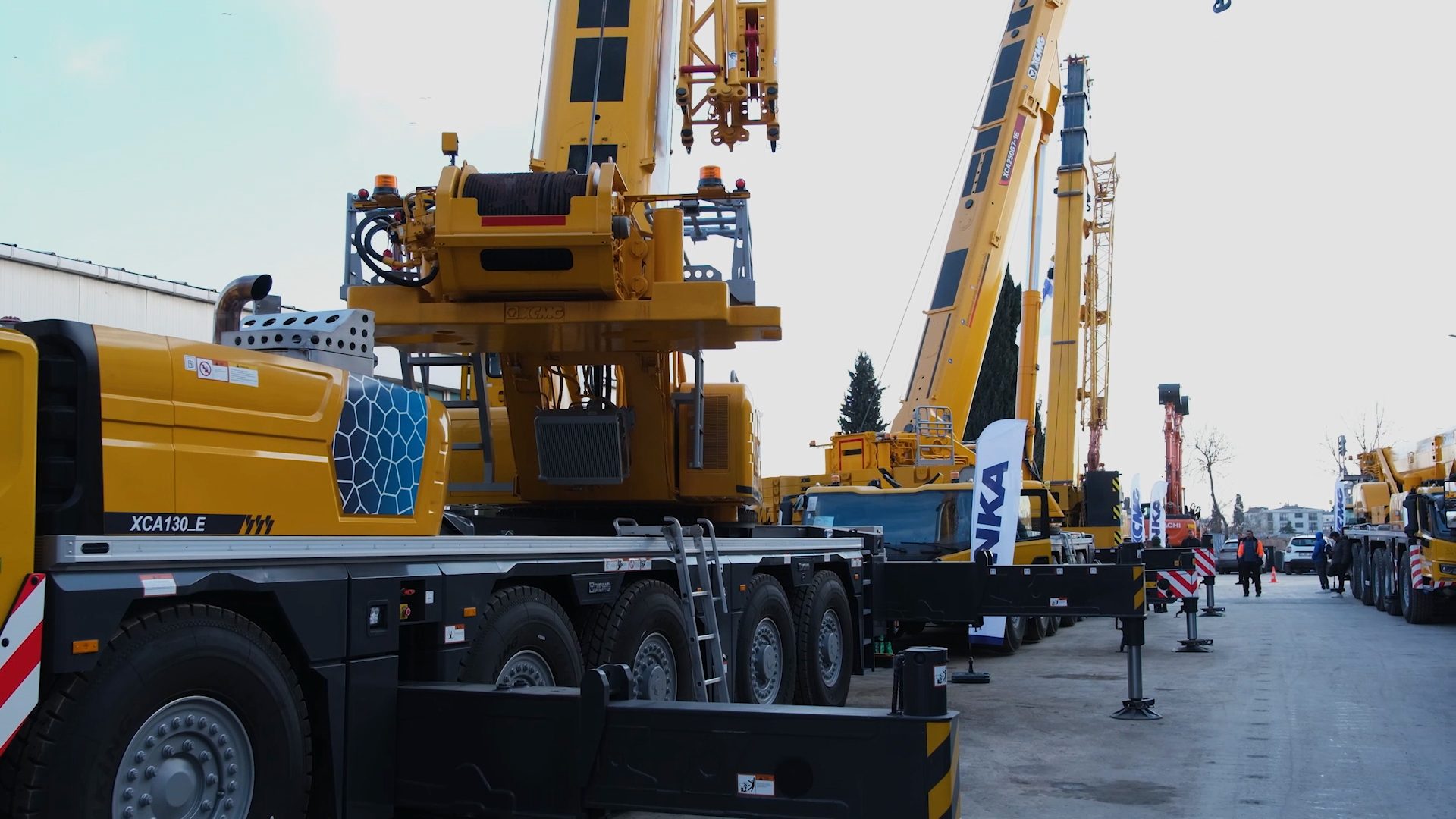Large yellow XCMG construction cranes displayed outdoors, with the XCA130_E model prominent in the foreground.
