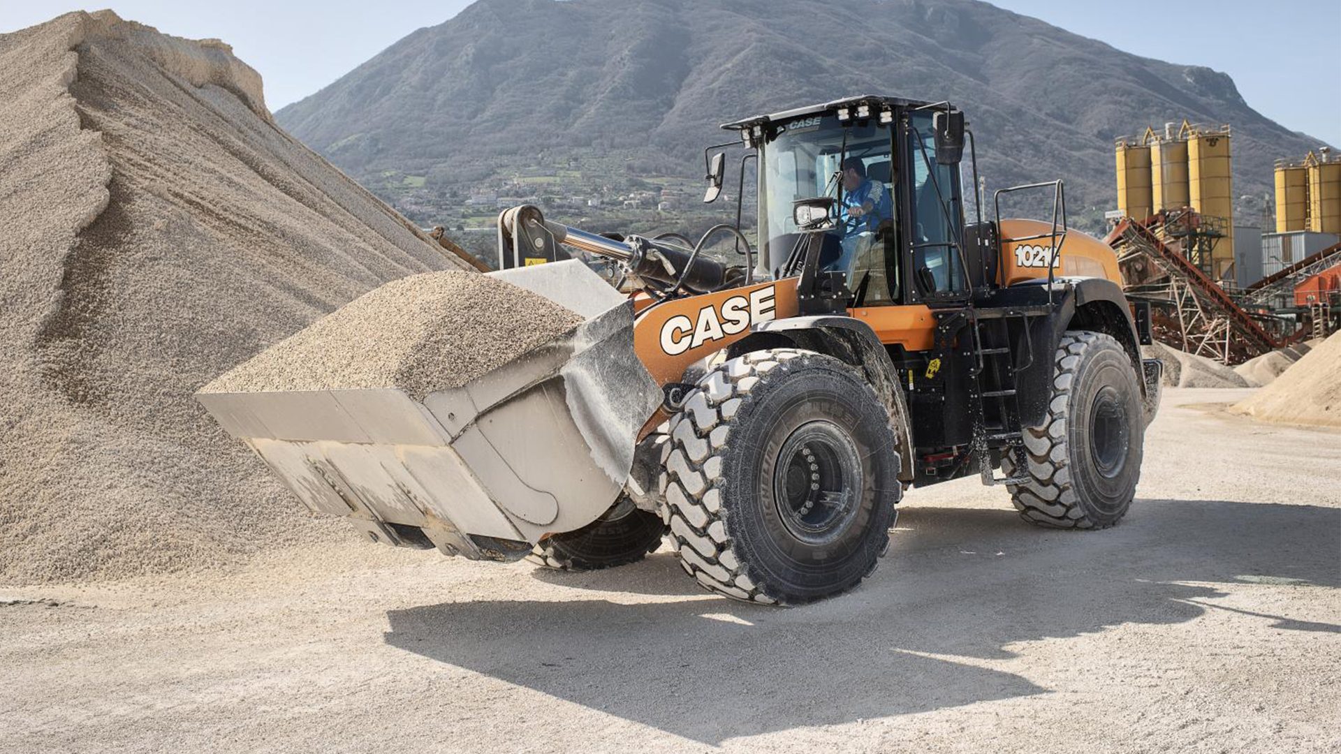 CASE 1021 wheel loader with gravel-filled bucket at a quarry site.
