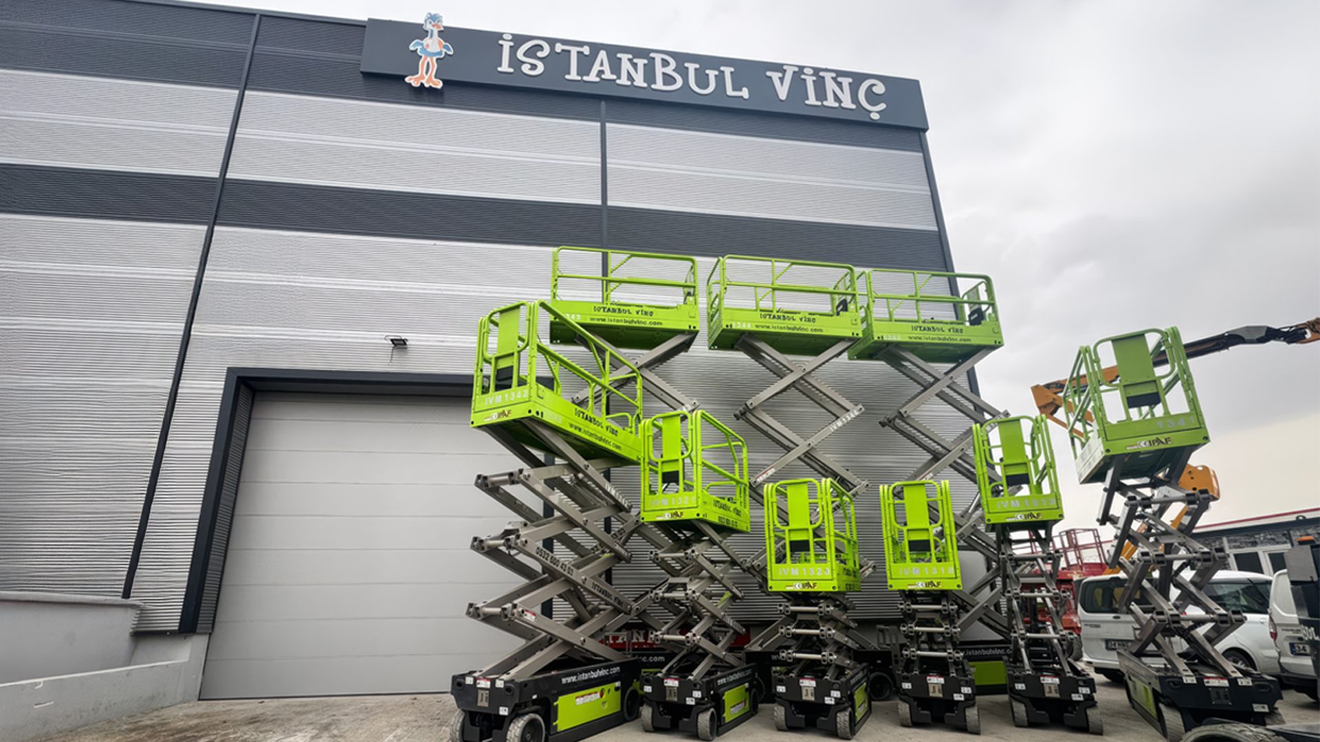 İSTANBUL VİNÇ building with its sign and several green scissor lifts parked outside.