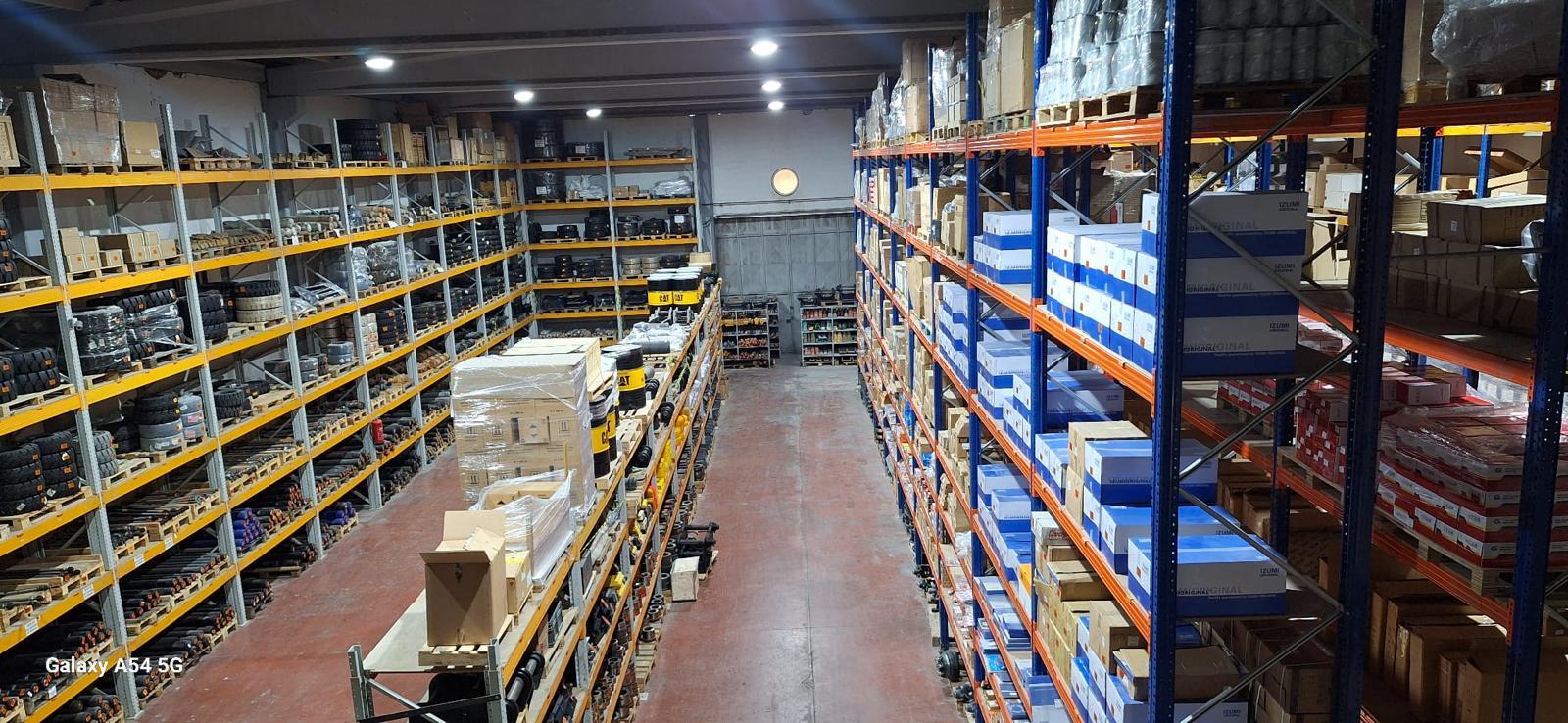 Large warehouse with tall shelves packed with various products along multiple aisles.