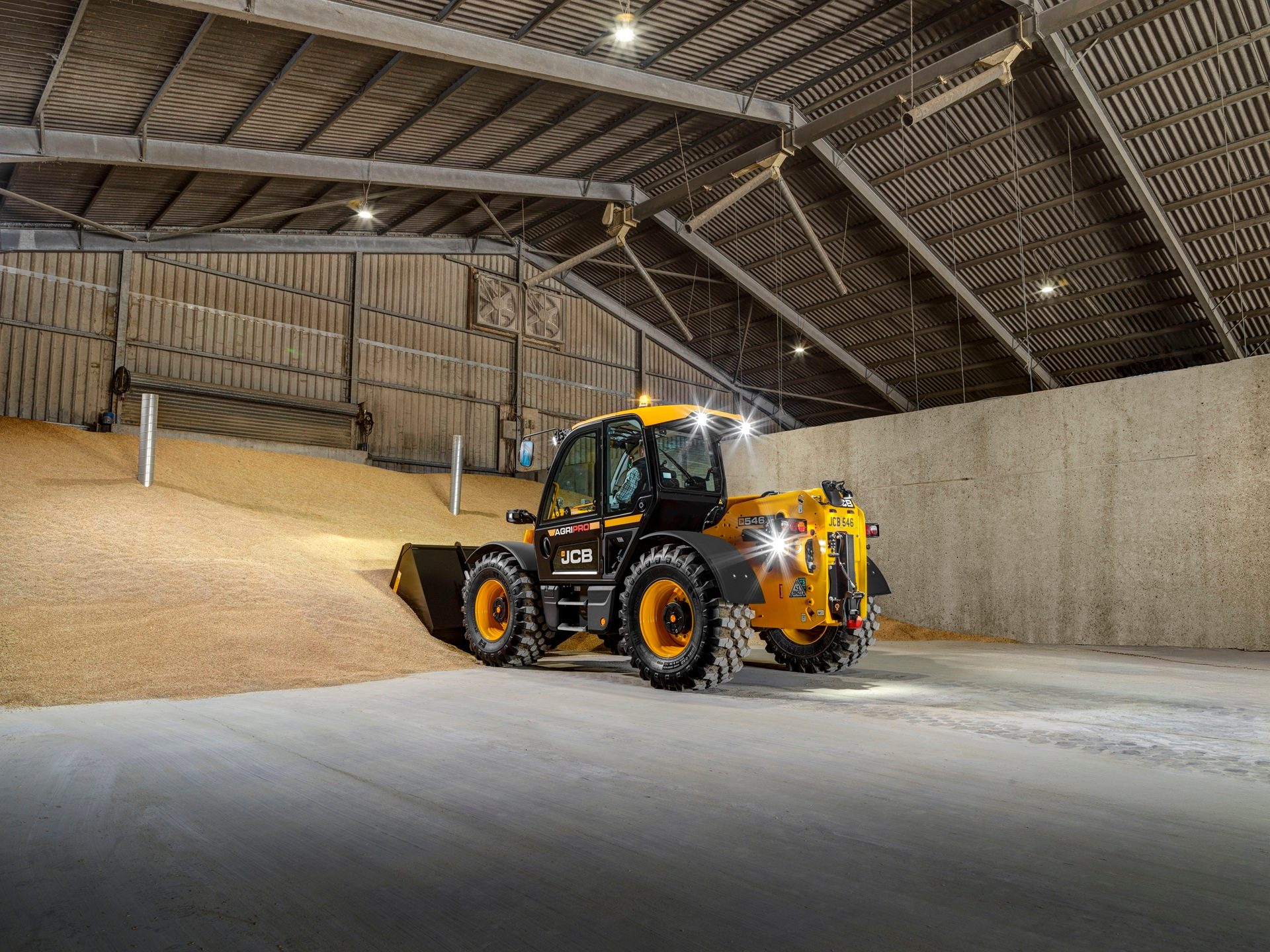 Yellow JCB telehandler in a grain storage barn.