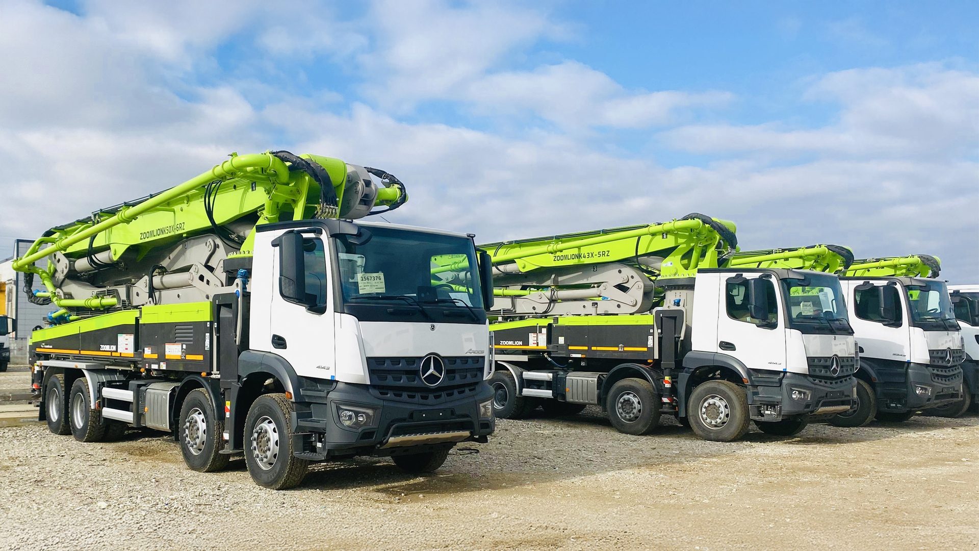 Line of white Mercedes-Benz concrete pump trucks with green Zoomlion booms.
