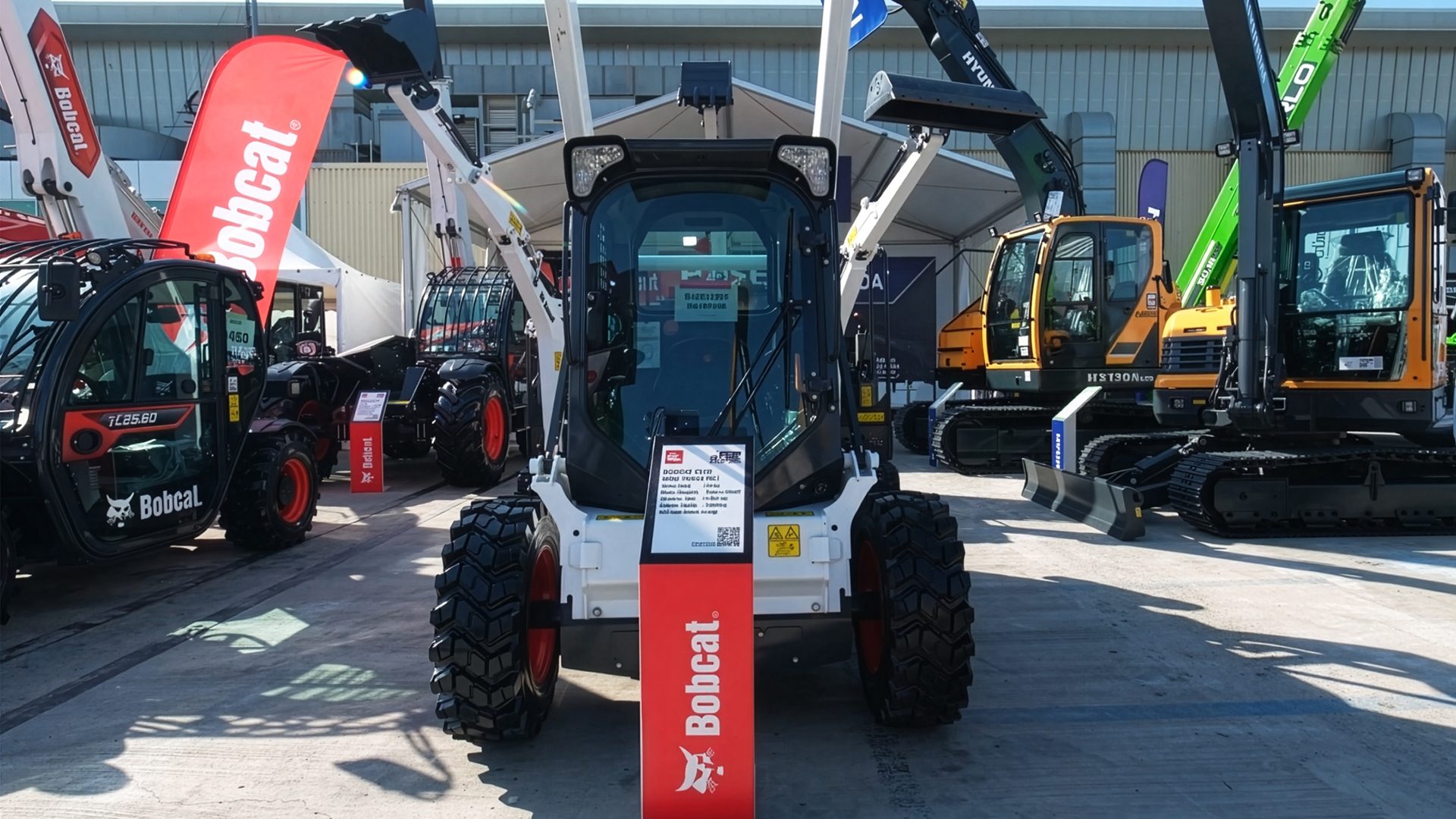 Heavy equipment: Bobcat skid-steer loader, telehandler, and Hyundai excavators on display.