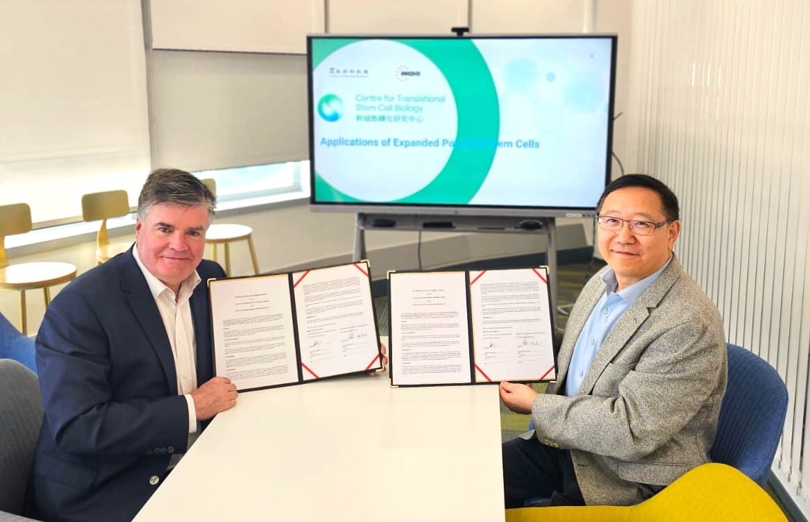 Two men hold signed agreements; screen shows 'Translational Stem Cell Biology'.
