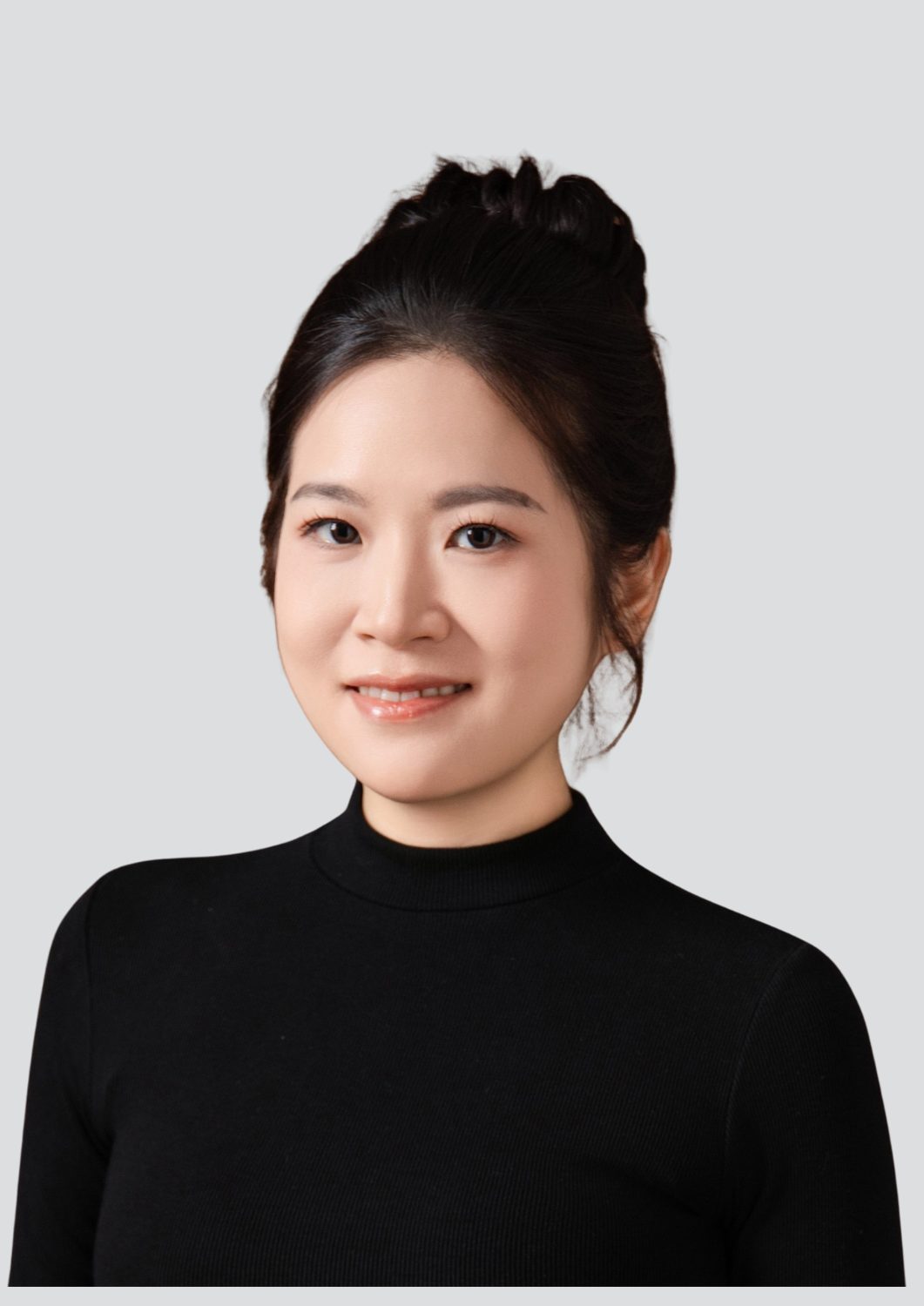 Smiling woman in black turtleneck against a gray background.